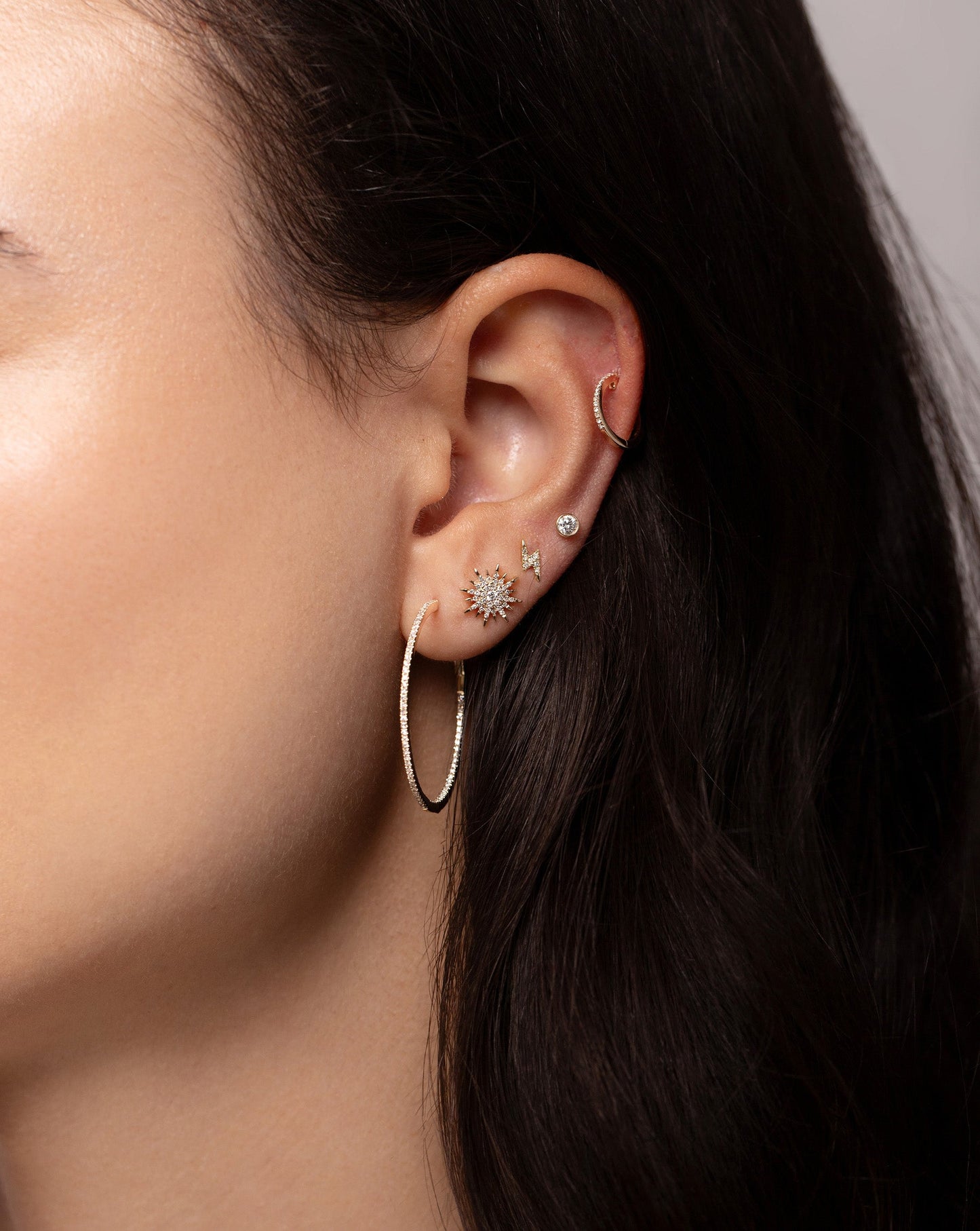 Starburst Diamond Studs stacked on ear with the Diamond Hoops, Mini Lightning Bolt Studs, Bezel Set Petite Diamond Studs and the Diamond Huggies