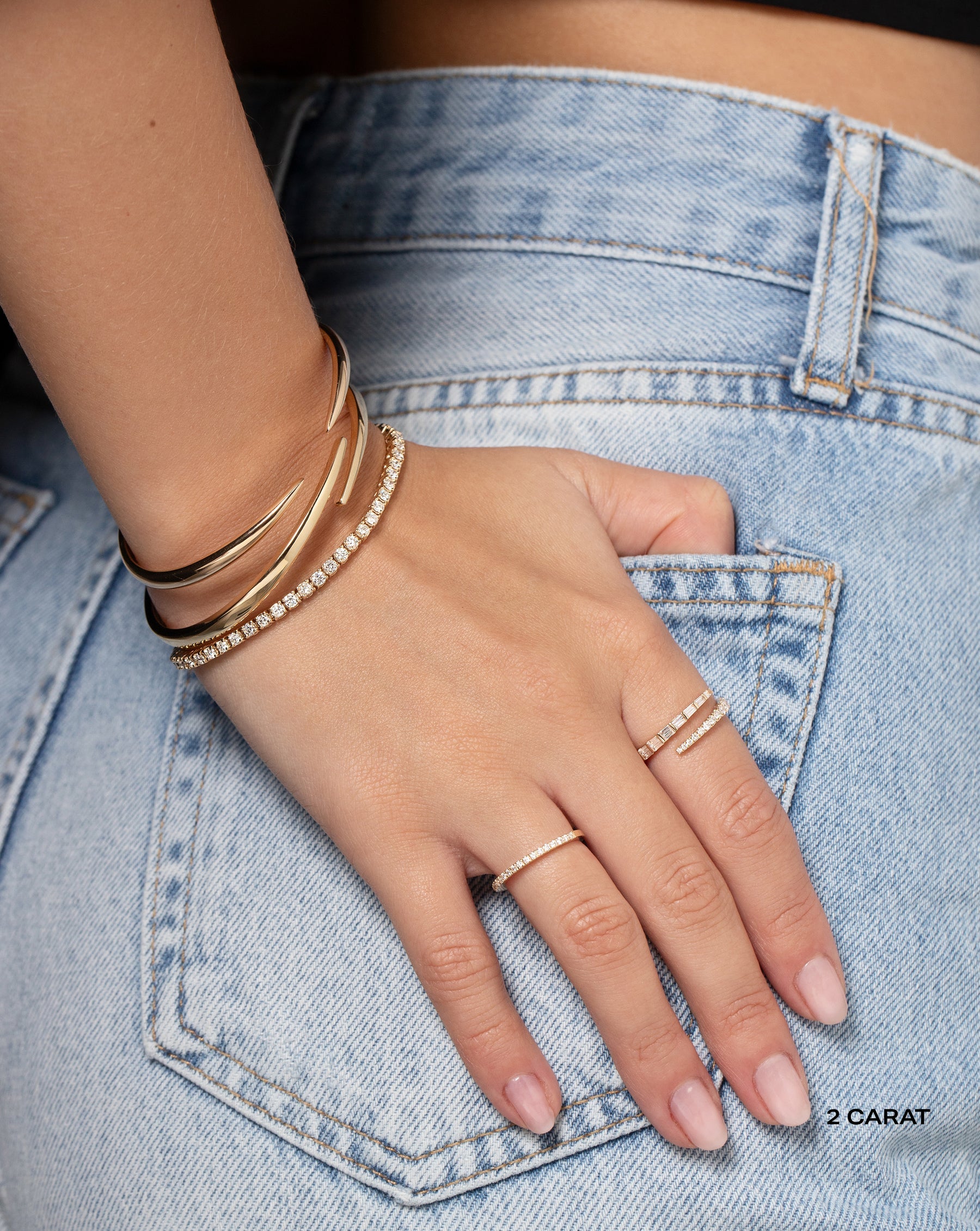 Model with hand on back pockets wearing 3 Ring Concierge bracelets and 2 rings