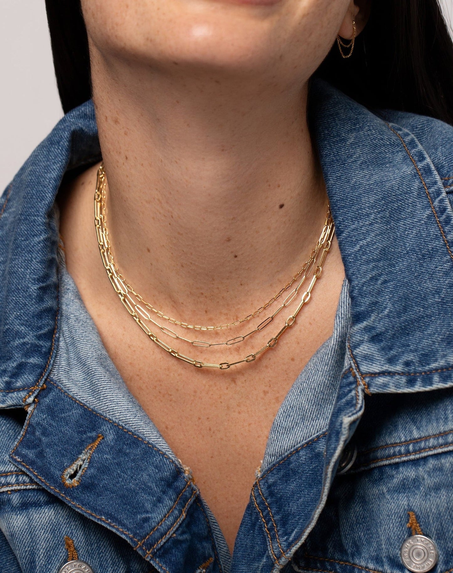 Long Link Chain Necklace styled with 2 other link chain necklaces on model wearing denim jacket