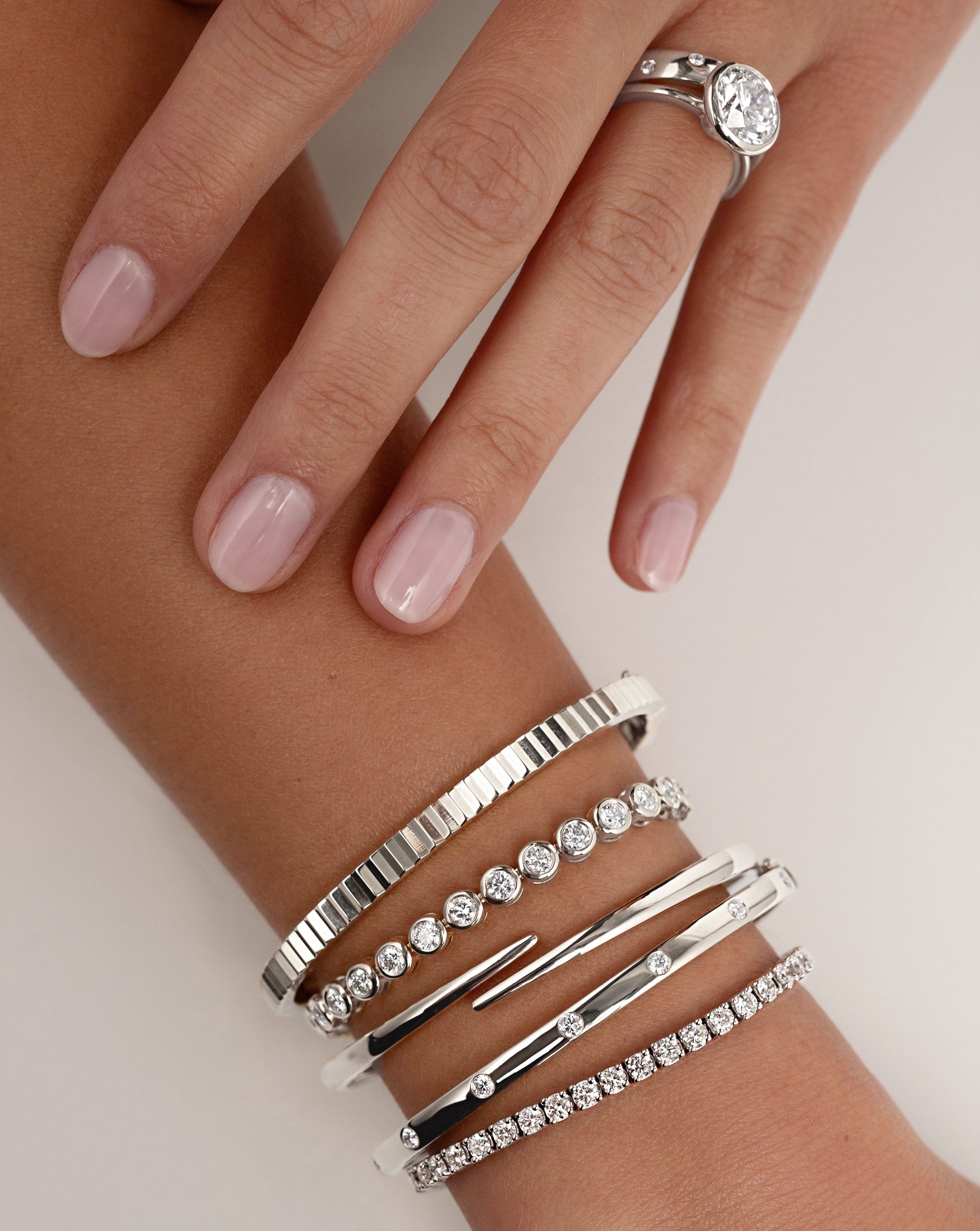 Bezel-Set Classic Diamond Tennis Bracelet, Inlay Diamond Bangle, Open Wrap Gold Bangle, Fluted Gold Bangle and Classic Diamond Tennis Bracelet all in White Gold on model