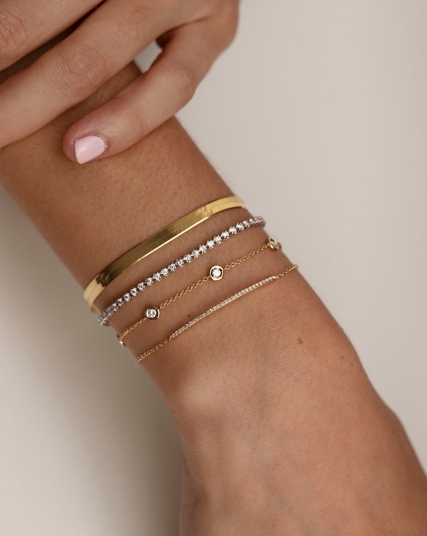 four diamond and gold bracelets stacked on model. global