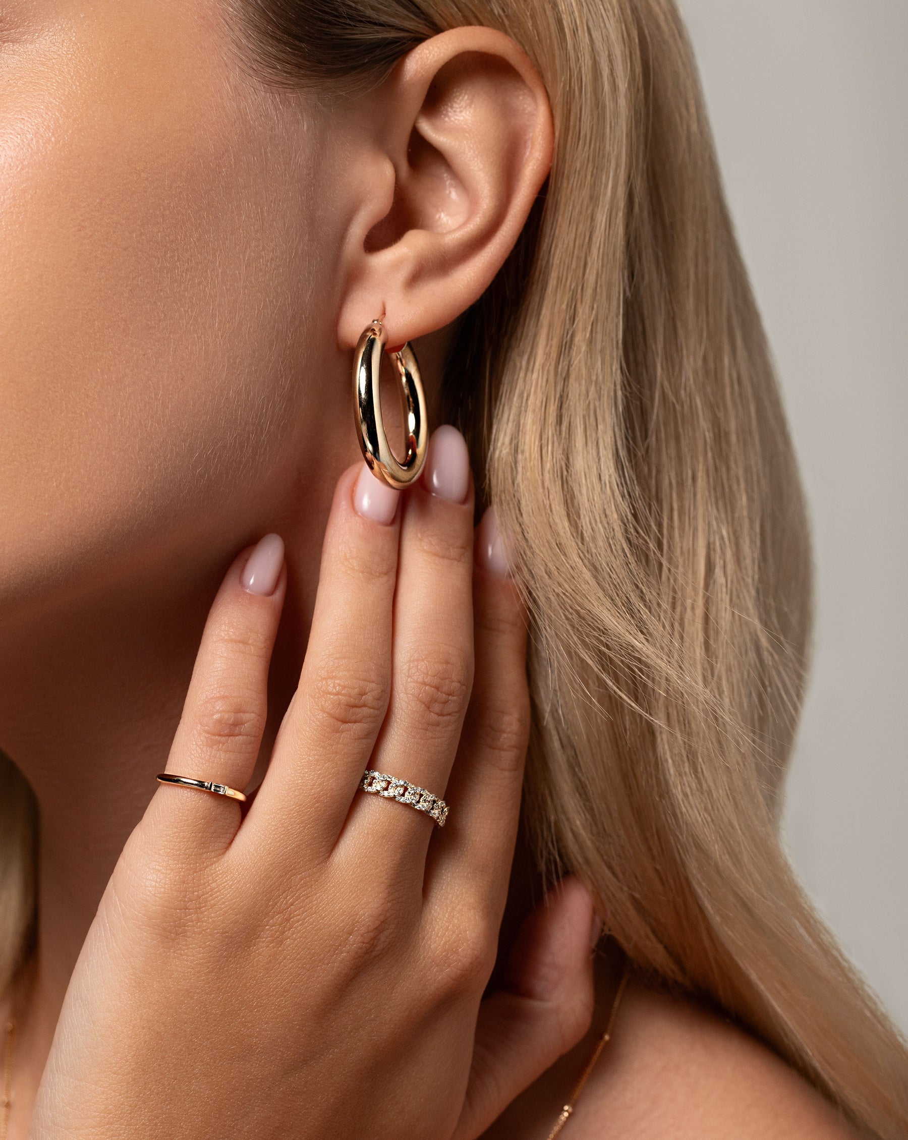 Pavé Diamond Chain Ring in 14k yellow gold worn with the Single Baguette Diamond Ring touching neck near tube hoops in ear