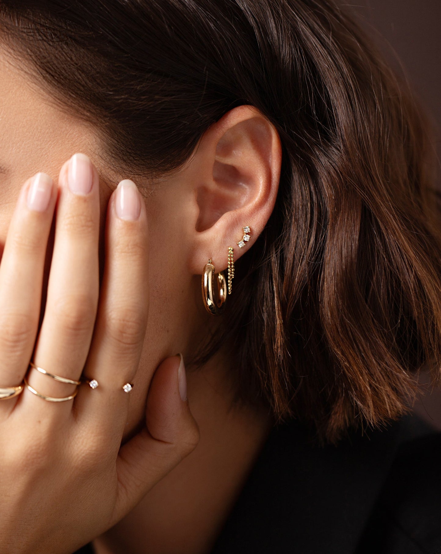 4 mm Gold Tube Hoops shown on ear of model with the Bead Chain Front to Back Studs and Curved Trio Diamond Studs