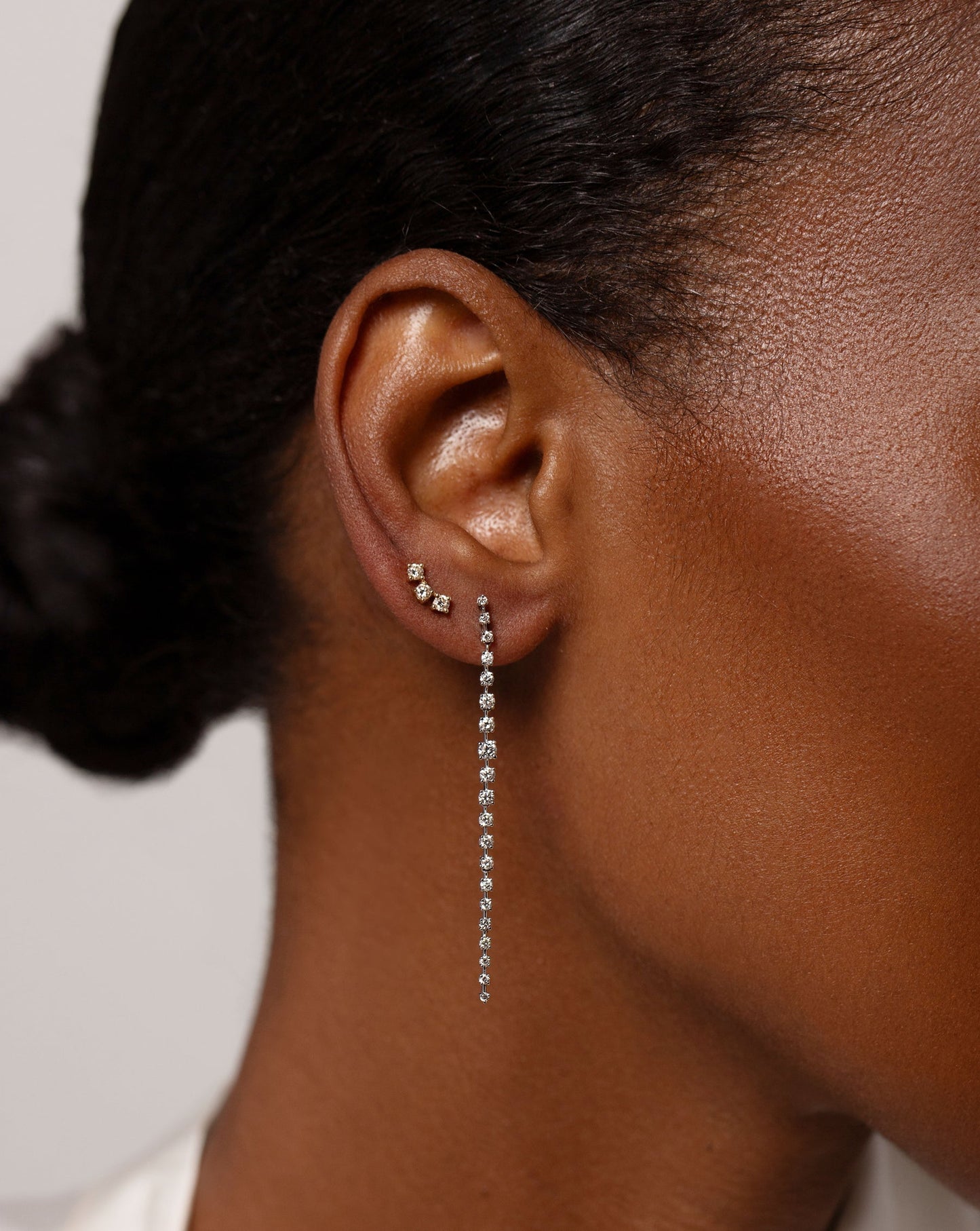 three stone diamond curved studs and graduated diamond drop earrings shown on model