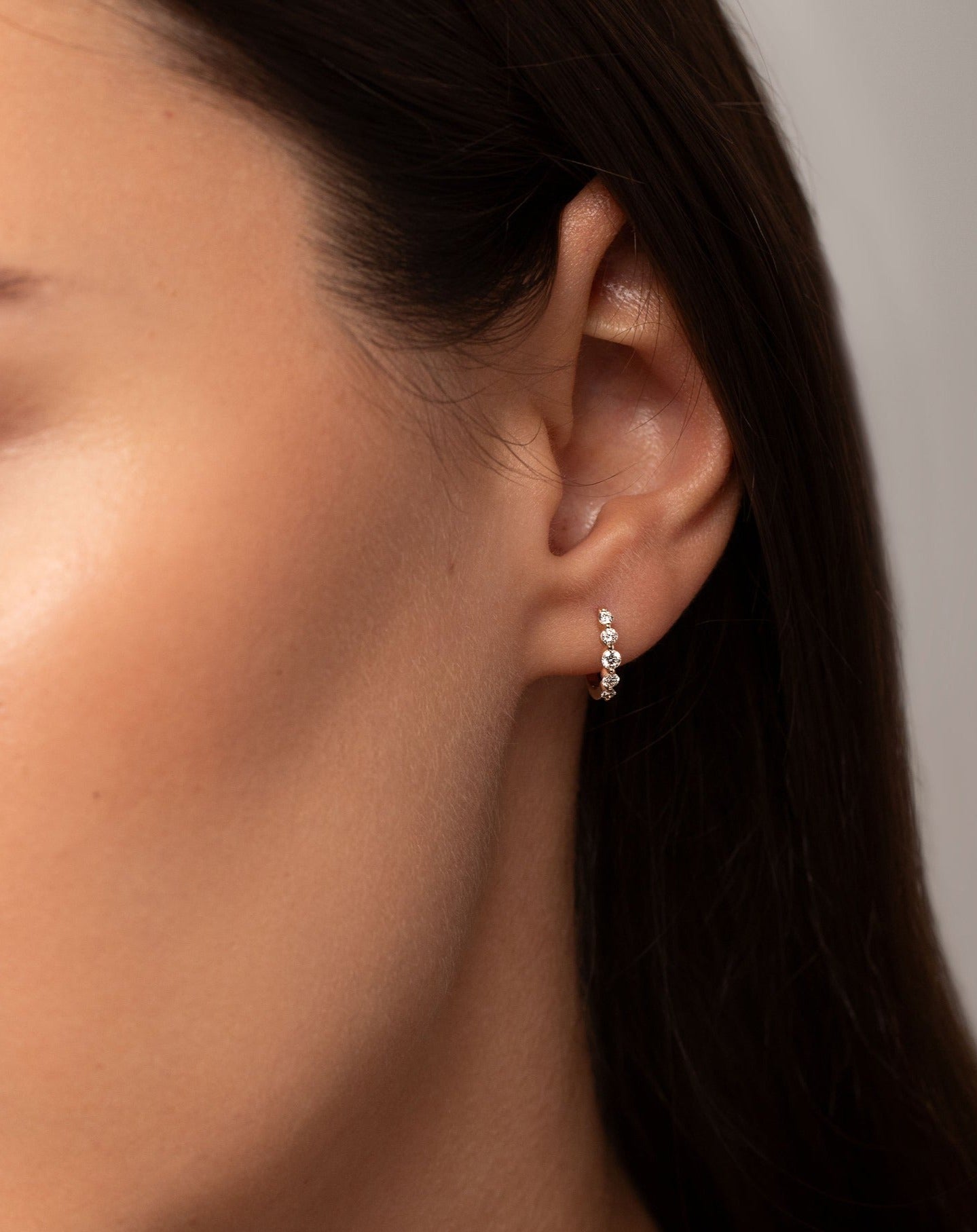 Graduated single prong diamond huggies shown on model