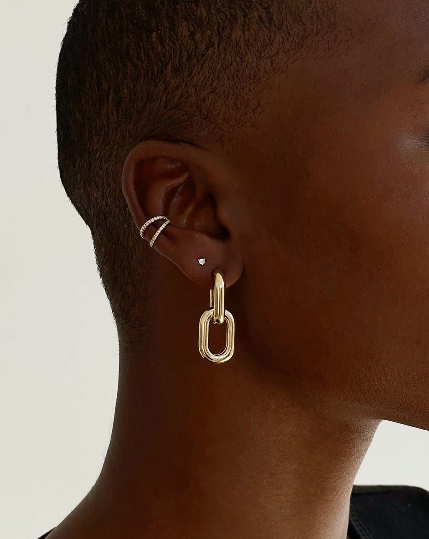 double row diamond ear cuff, tiny round-cut diamond stud, and large gold double link earring shown on model