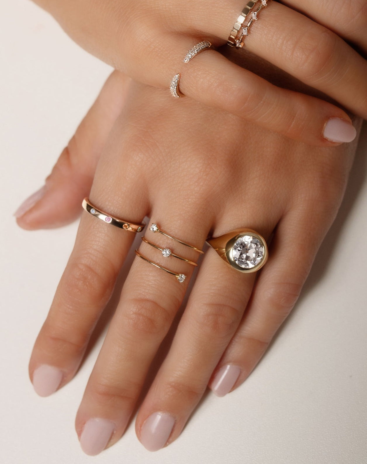 14k yellow gold band with inlay birthstones, triple wrap gold wire ring with three diamonds, bezel-set round diamond engagement ring, pave diamond claw ring, gold geometric ring, baguette-cut diamond distance ring and scattered diamond ring shown on model