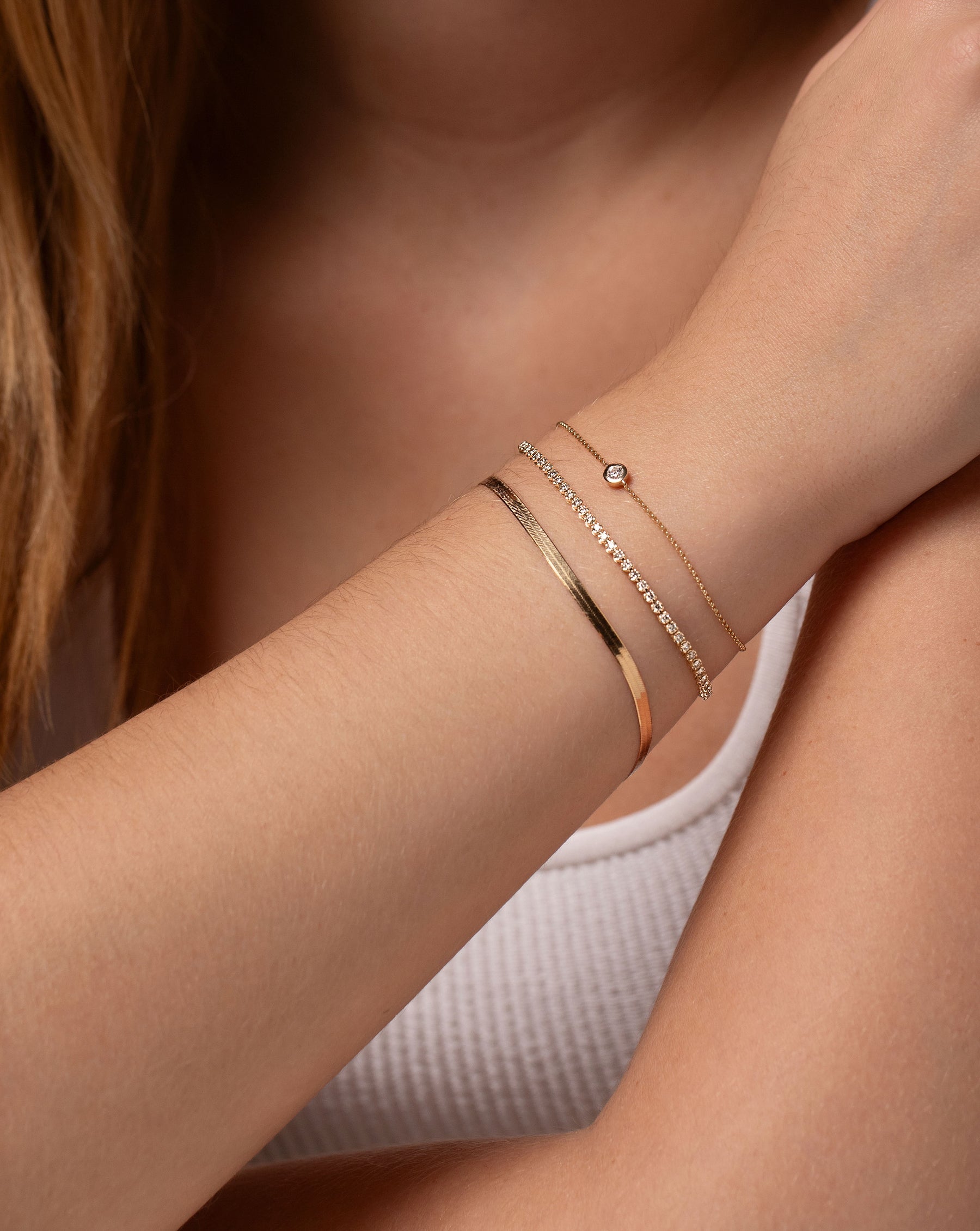herringbone chain bracelet, mini diamond tennis bracelet, and diamond bezel-set bracelet on model