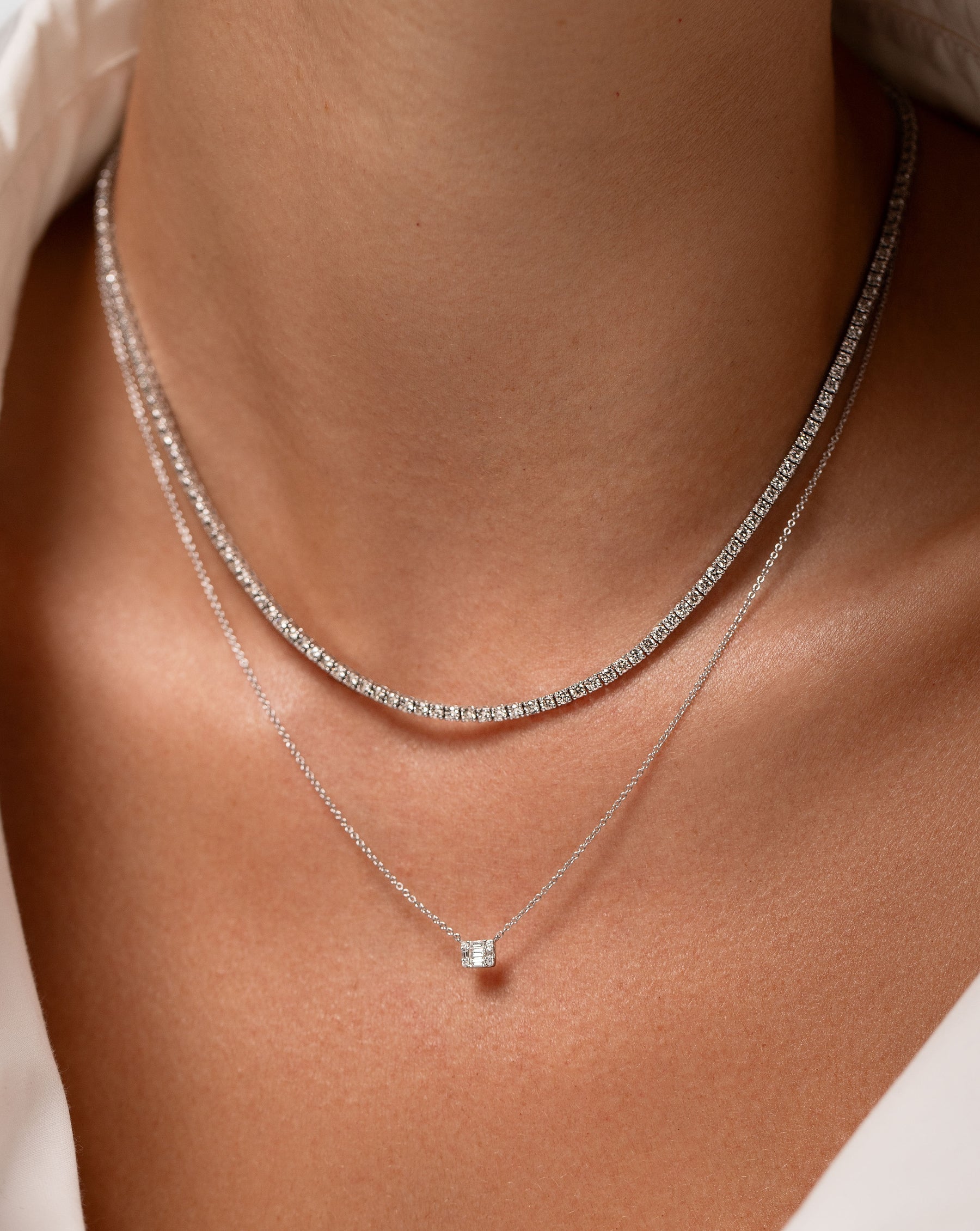 classic four prong set diamond tennis necklace and petite diamond emerald illusion pendant necklace shown on model