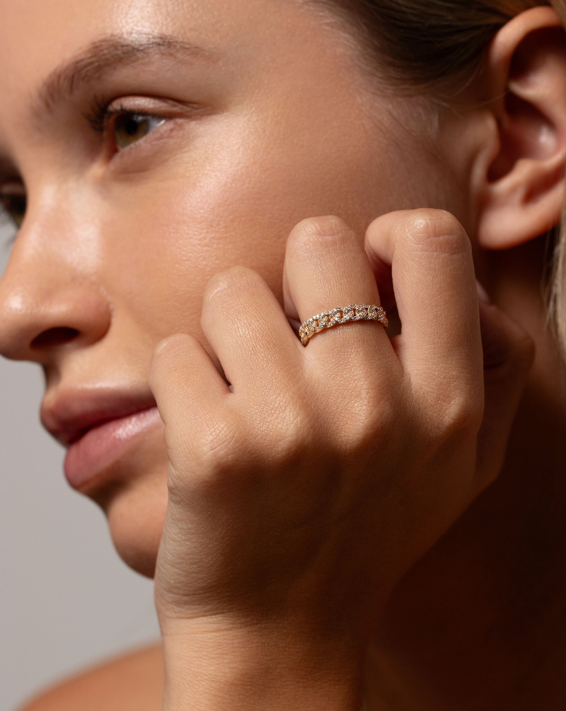 Pavé Diamond Chain Ring in 14k yellow gold worn on middle finger of hand resting on face