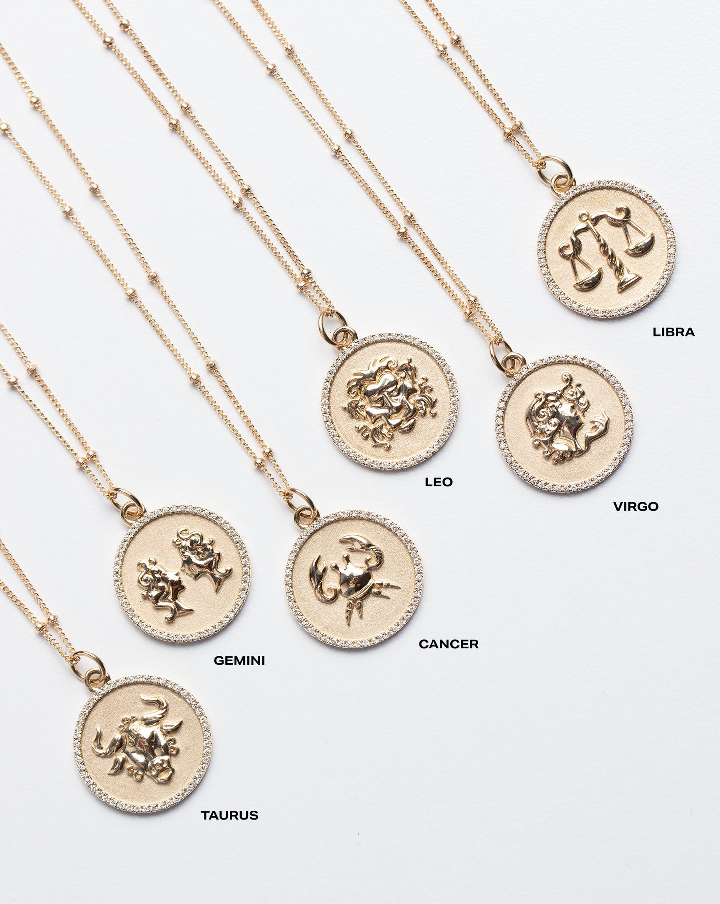 Flat lay of Zodiac Medallion Necklaces including Taurus, Gemini, Cancer, Leo, Virgo and Libra
