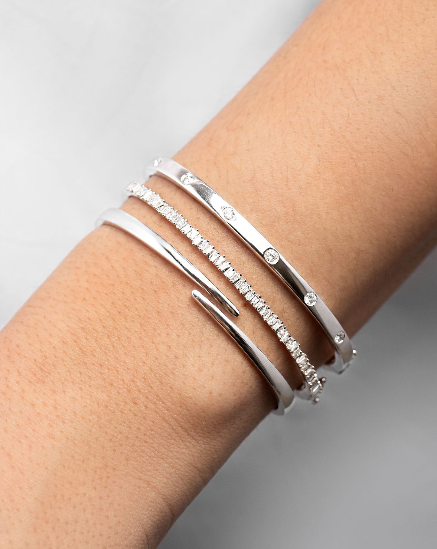 Open Wrap Gold Bangle in white gold on model styled with 2 other bangles