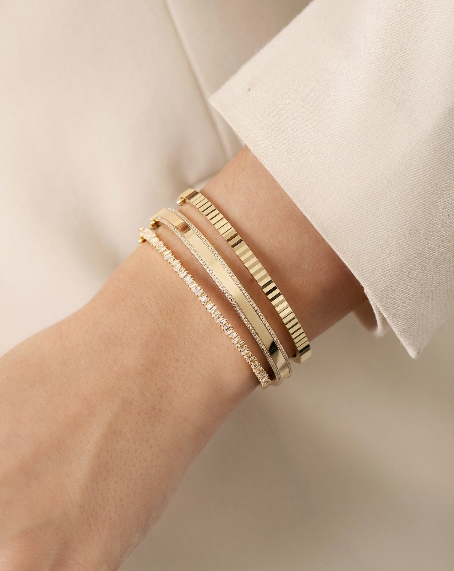 Baguette Ridge Bangle, diamond border bangle, and fluted bangle on model with blazer