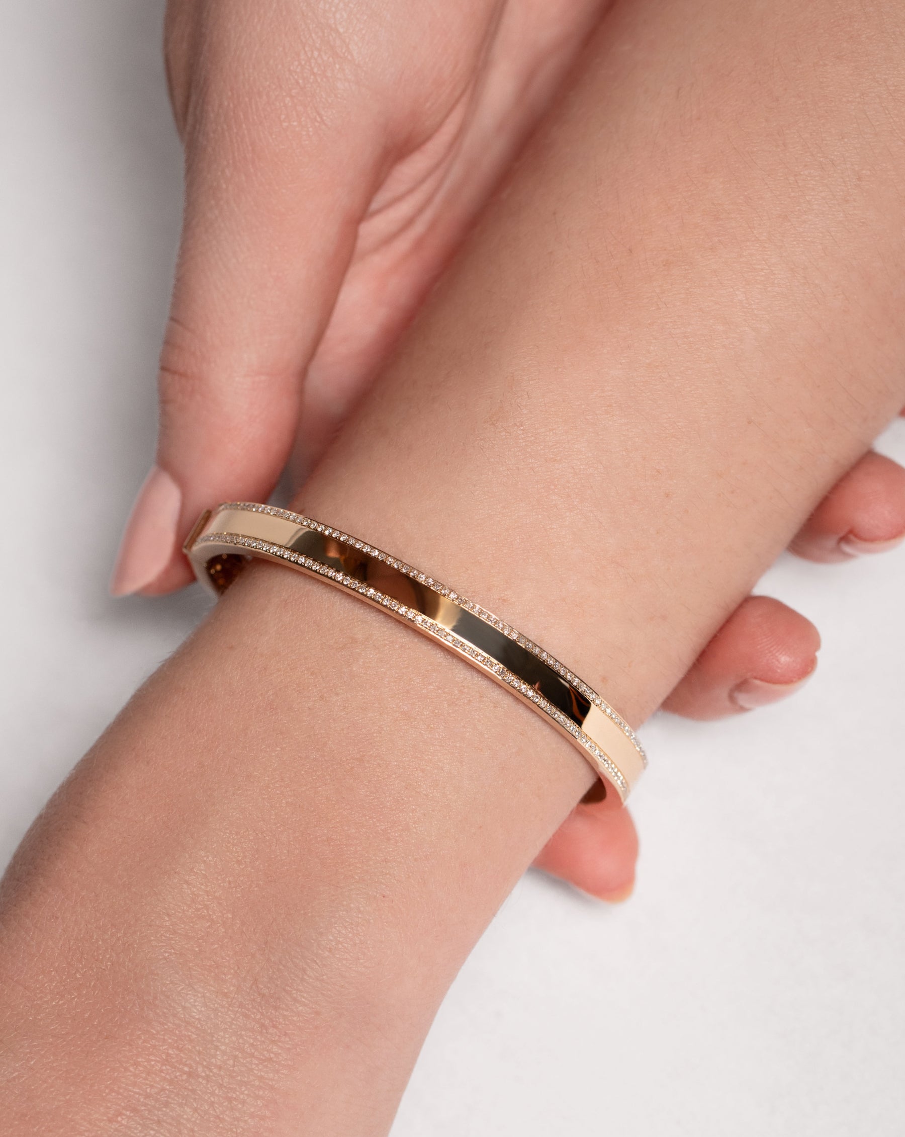 yellow gold and diamond bangle shown on a wrist