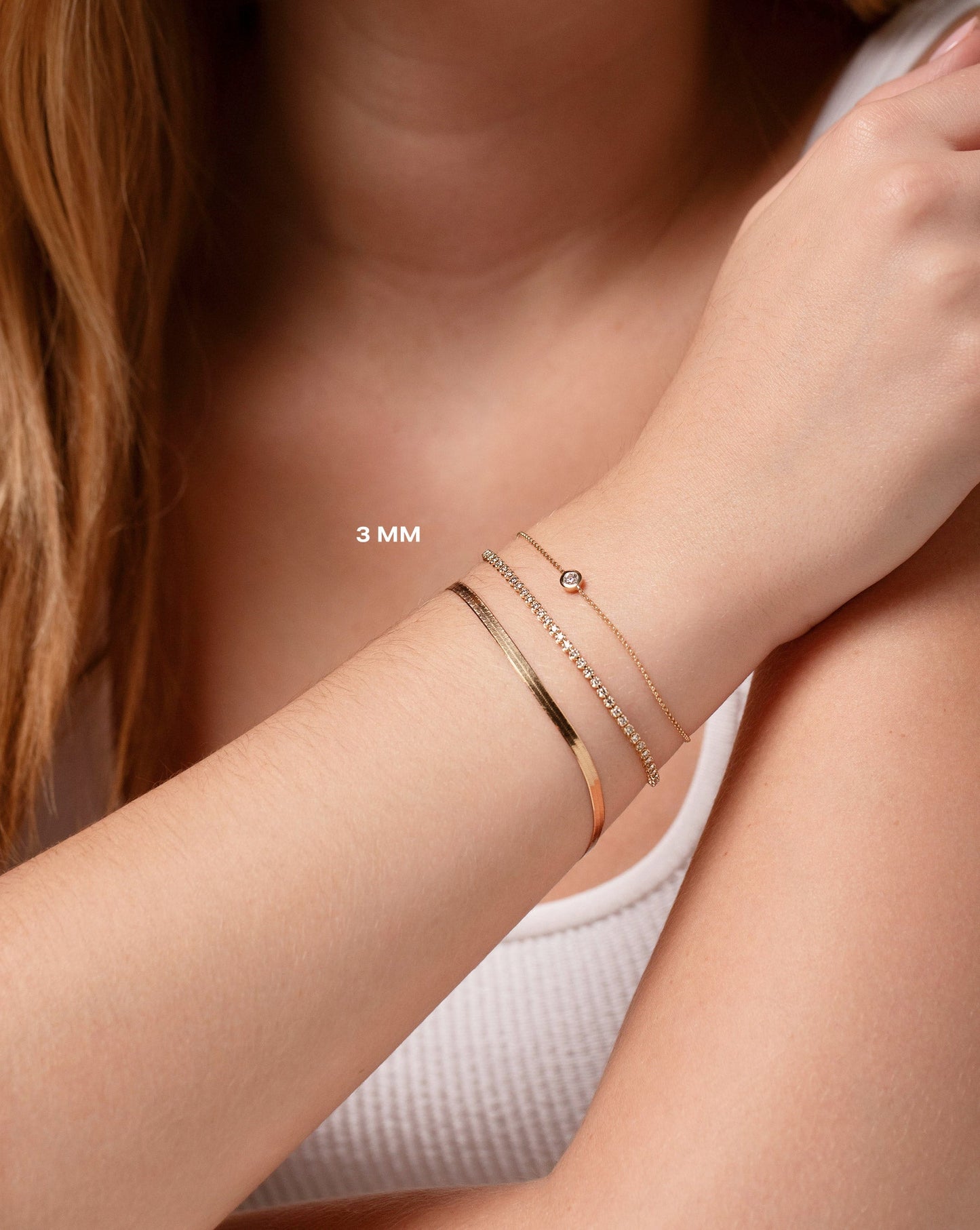 14k yellow gold herringbone chain bracelet, mini diamond tennis bracelet, and gold chain bracelet with bezel-set round diamond on model