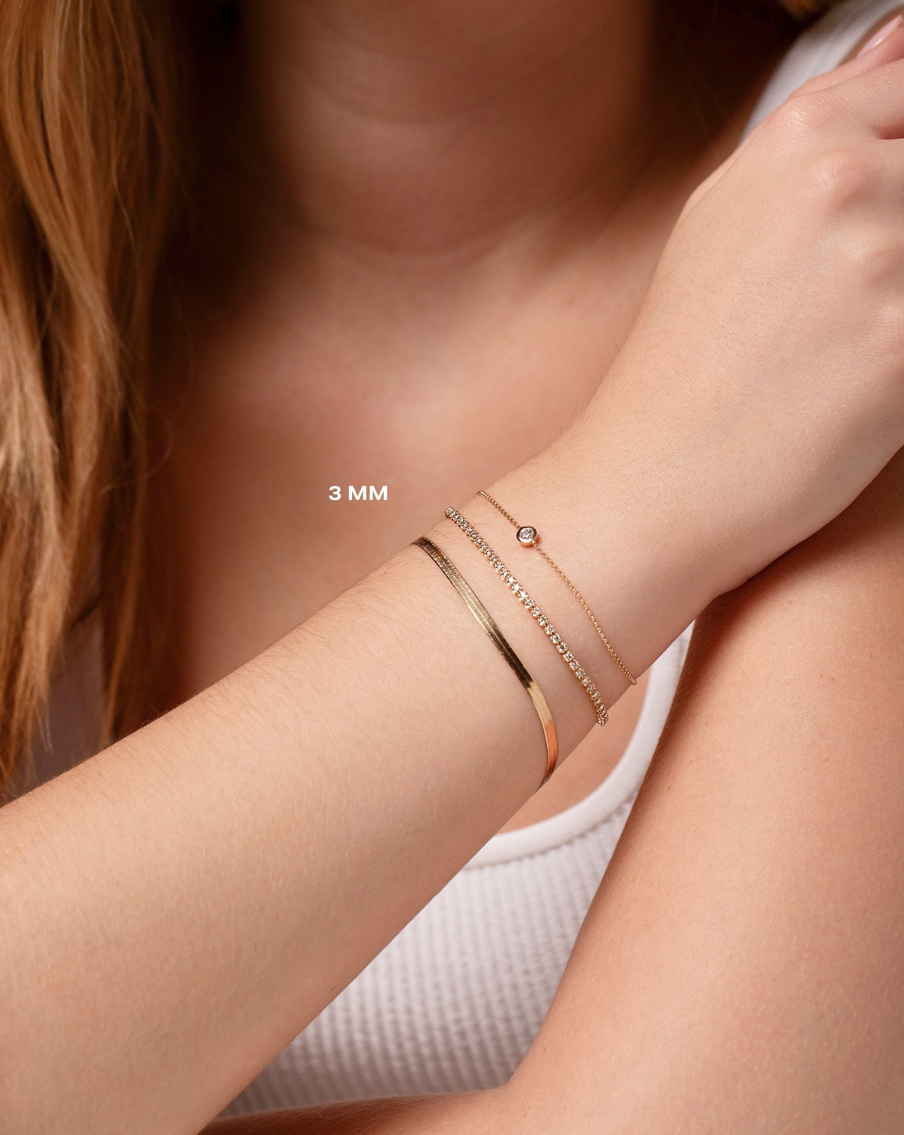 14k yellow gold herringbone chain bracelet, mini diamond tennis bracelet, and gold chain bracelet with bezel-set round diamond on model