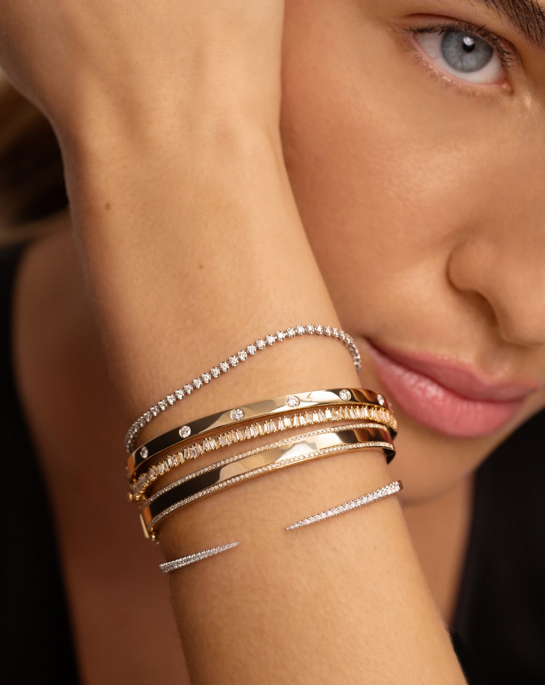 mini diamond tennis bracelet, three gold and diamond bangles, diamond claw cuff on model