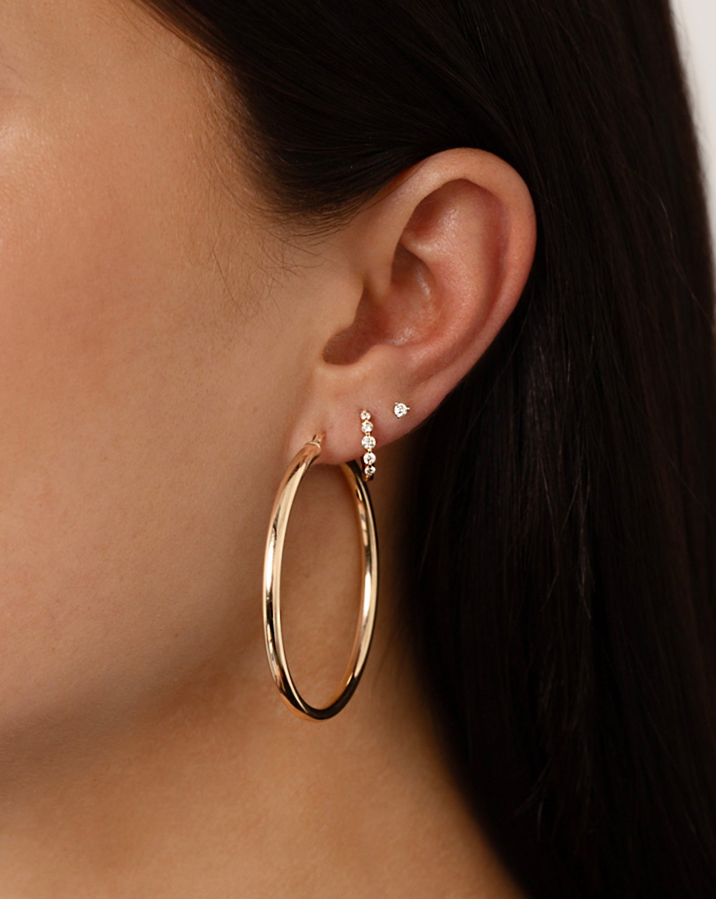 Graduated Single Prong Diamond Huggies styled with hoops and a stud on model