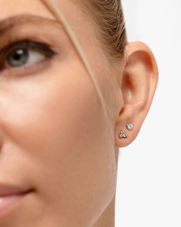 Bezel-Set Petite Diamond Studs with the Diamond Trio Studs shown as a close up on ear