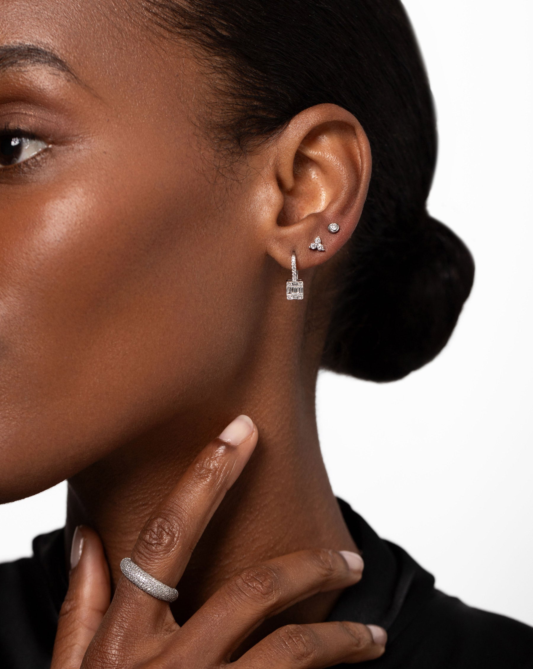 Bezel-Set Petite Diamond Studs on ear with the Emerald Illusion Lever Back Earrings and Diamond Trio Studs styled with the Pave Diamond Cloud Ring