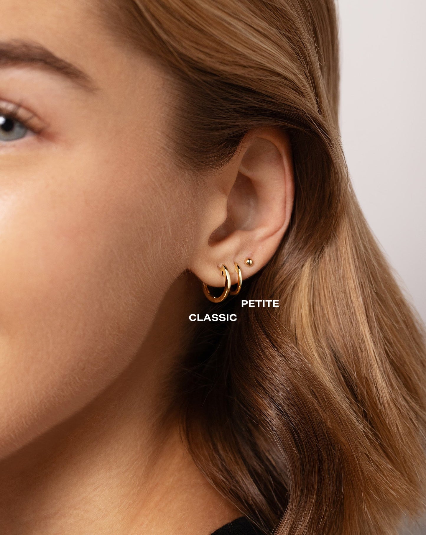 Close up image of the Classic Gold Huggies in both sizes worn with the Petite Gold Studs