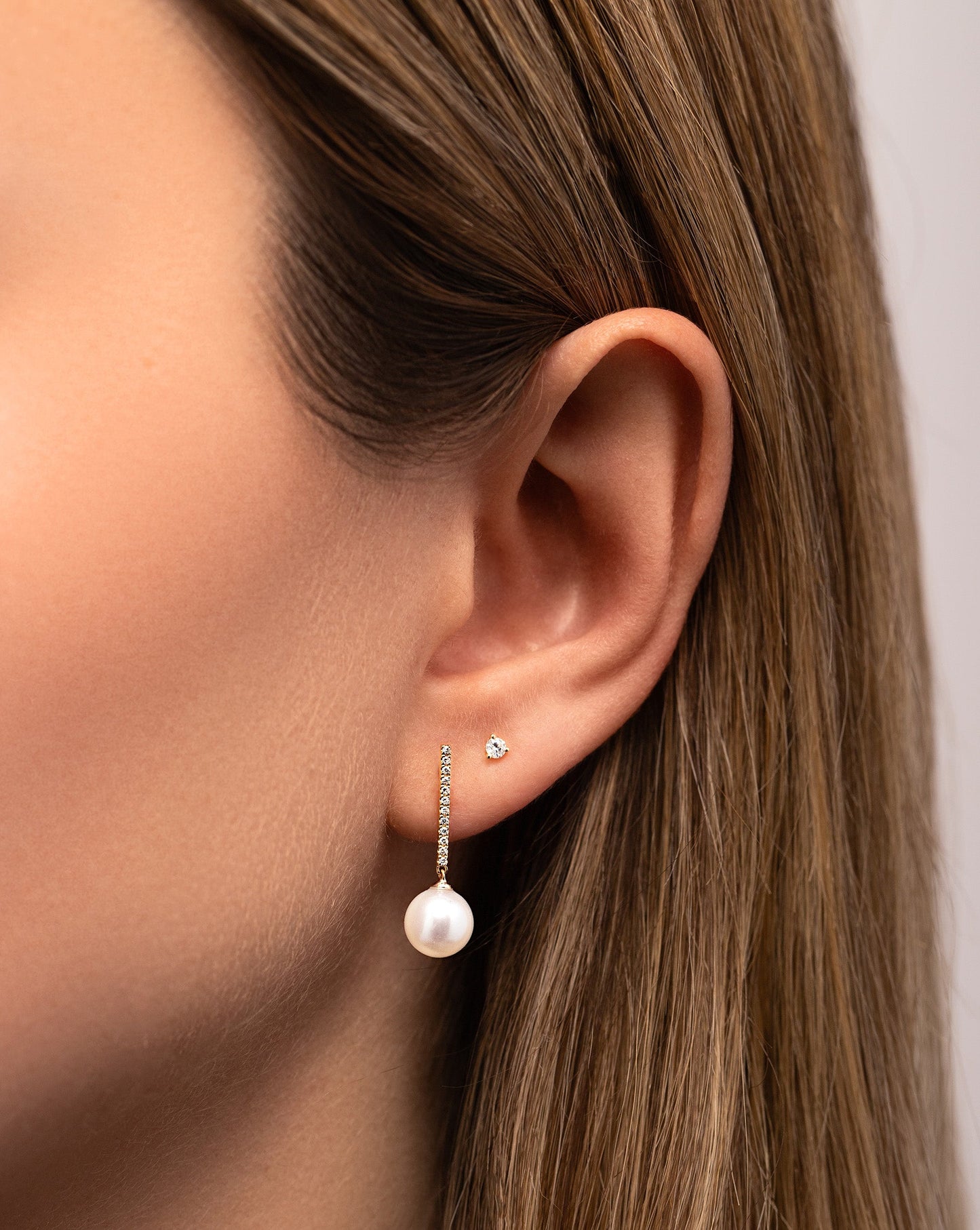 Diamond + Pearl Drop Earrings styled with tiny diamond studs on model