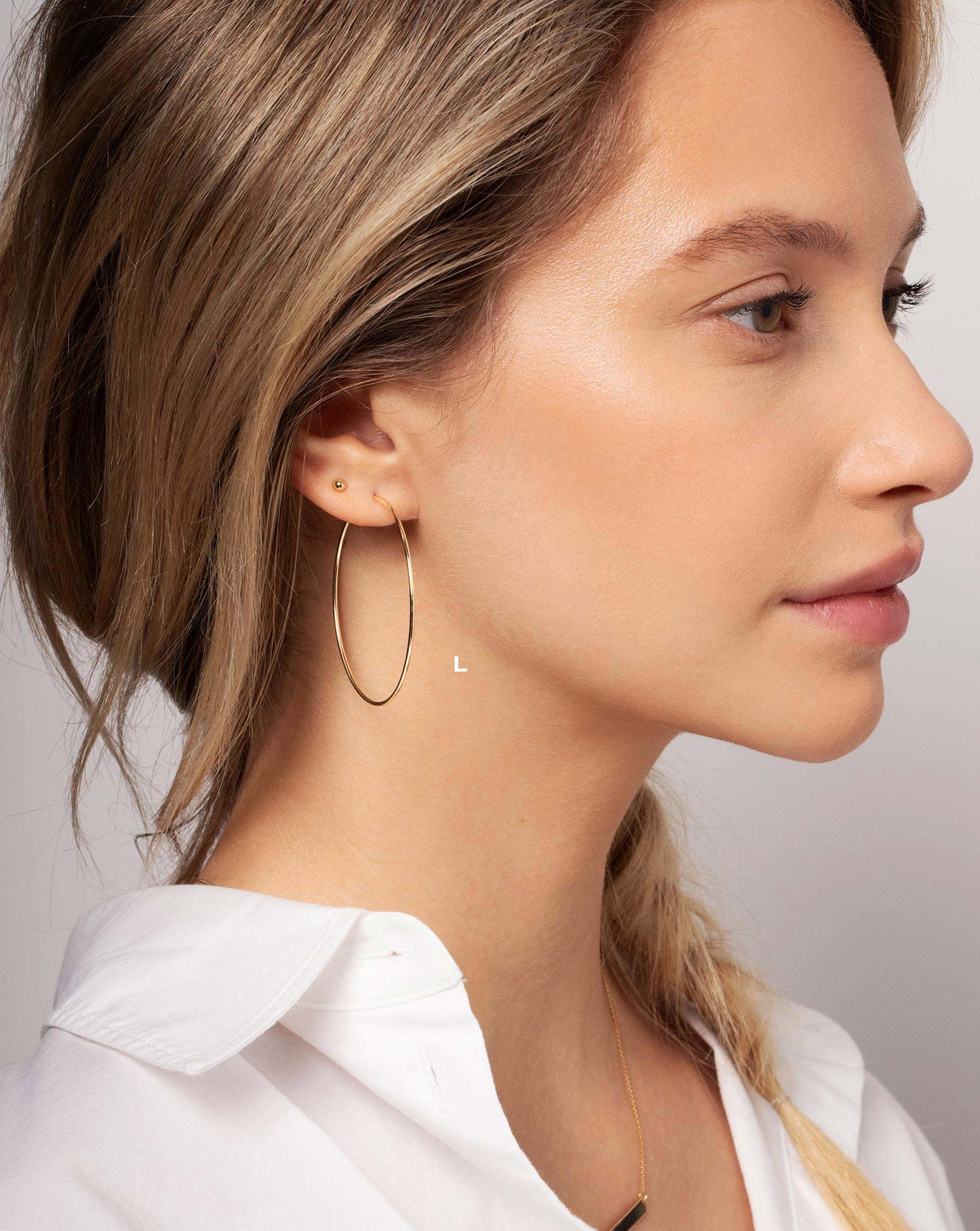 Size Large 1 mm Endless Gold Tube Hoops worn with the Petite Gold Bead Studs in ear of model