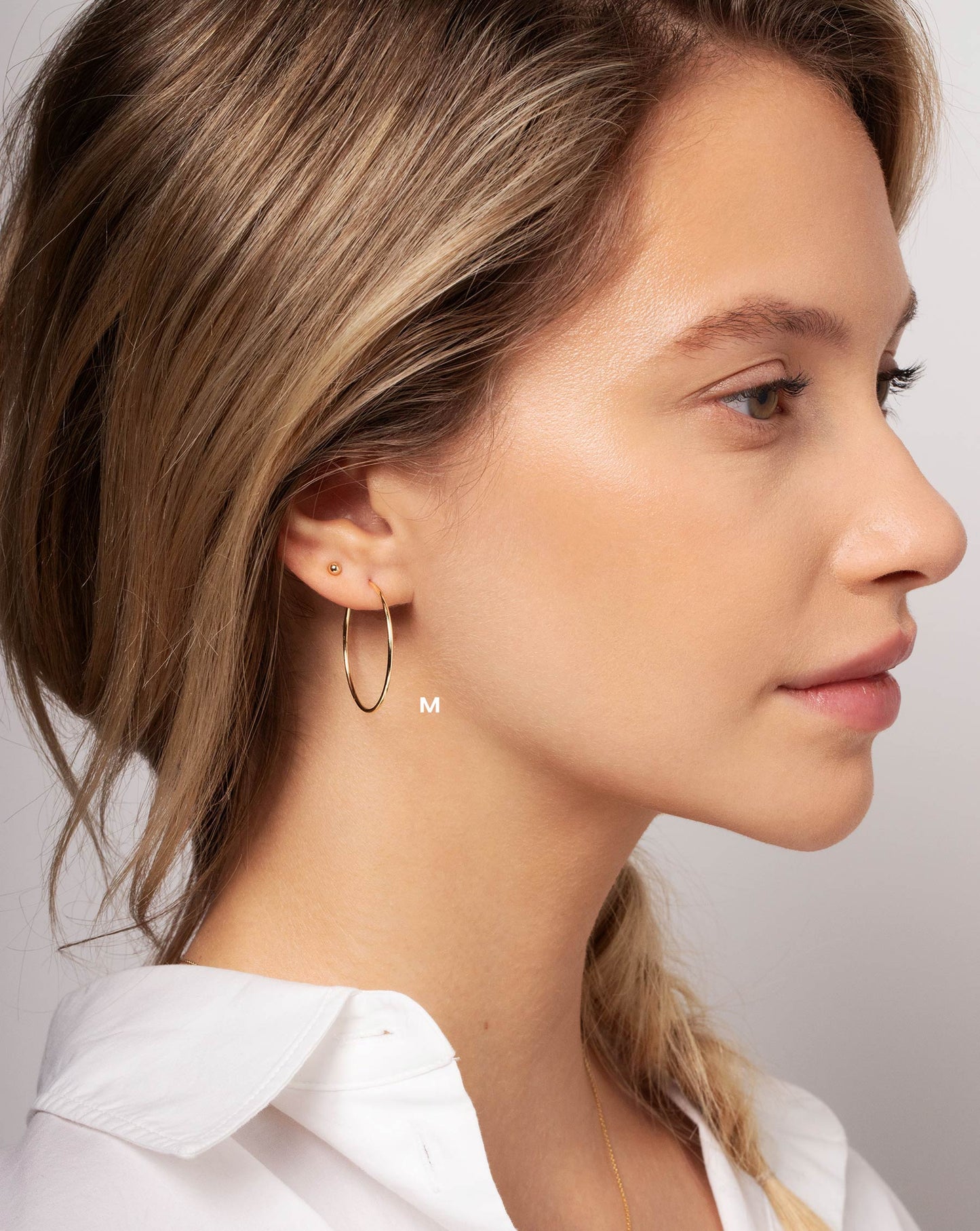 Size medium 1 mm Endless Gold Tube Hoops worn with the Petite Gold Bead Studs in ear of model