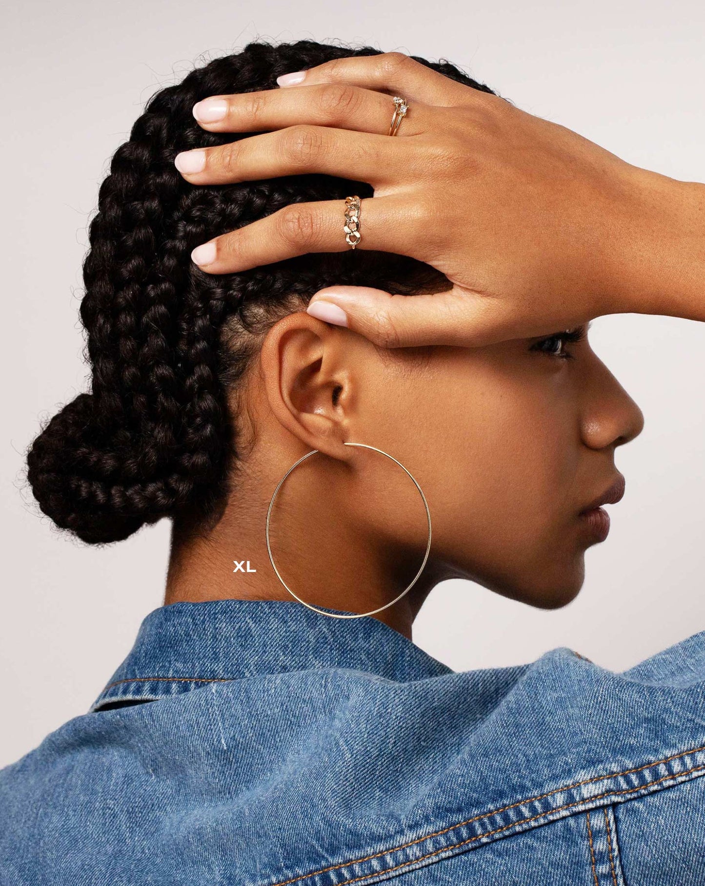 Size extra large 1 mm Endless Gold Tube Hoops worn on ear of model. Model is also wearing the Flexible Gold Curb Chain Ring and the Single Pear and Emerald Diamond Rings.