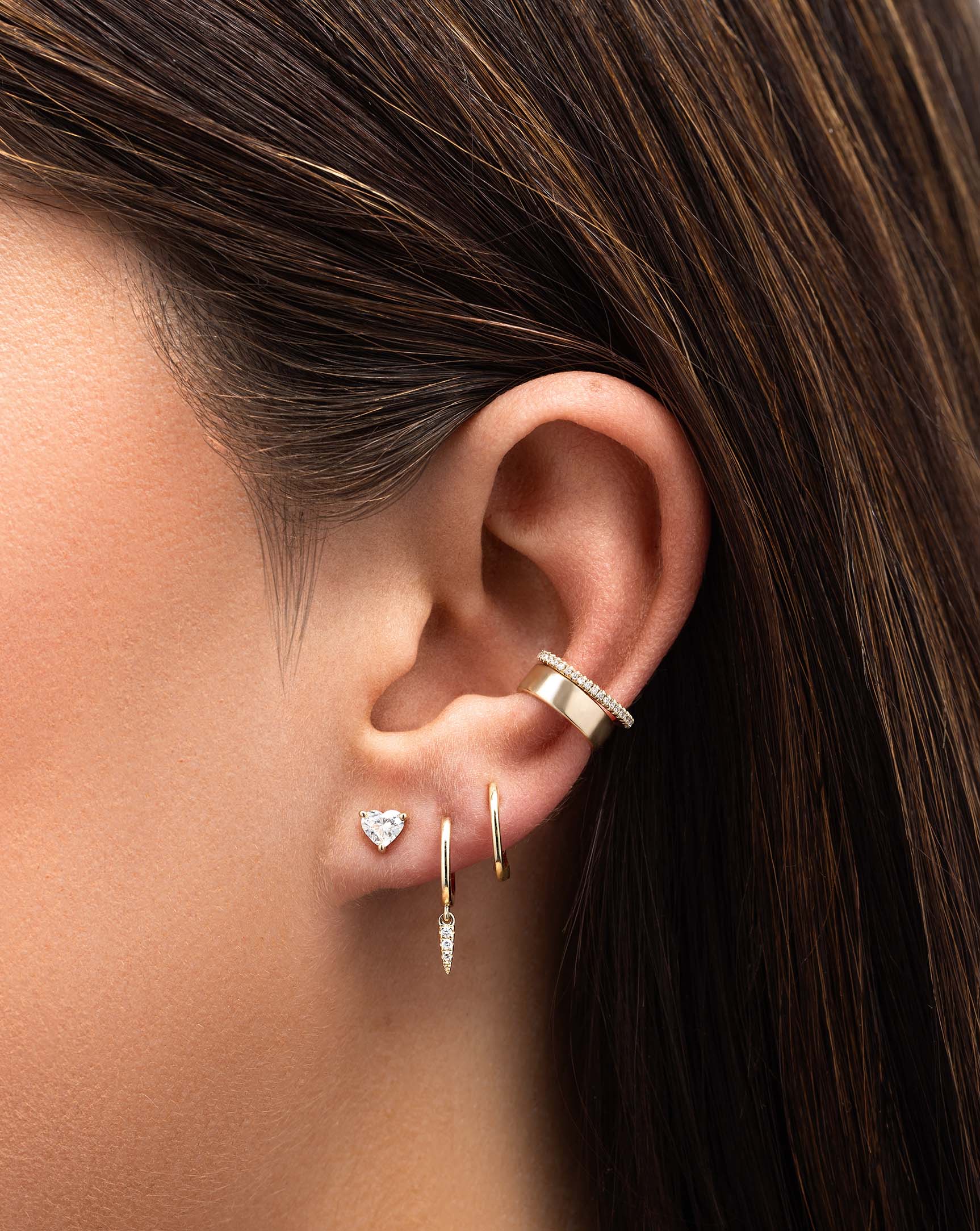 Diamond Ear Cuff styled with bold gold flat ear cuff and 3 other earrings on model
