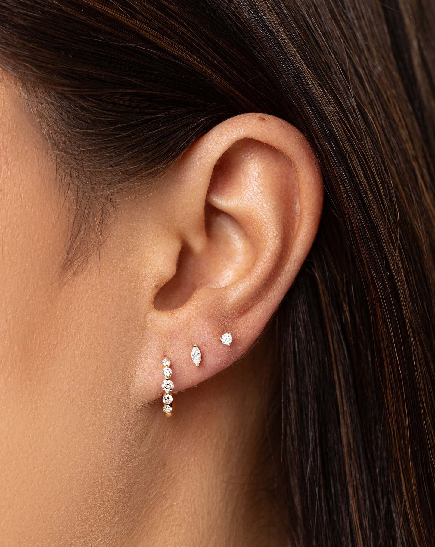 Graduated Single Prong Diamond Huggies styled with tiny marquise stud and tiny diamond stud on model