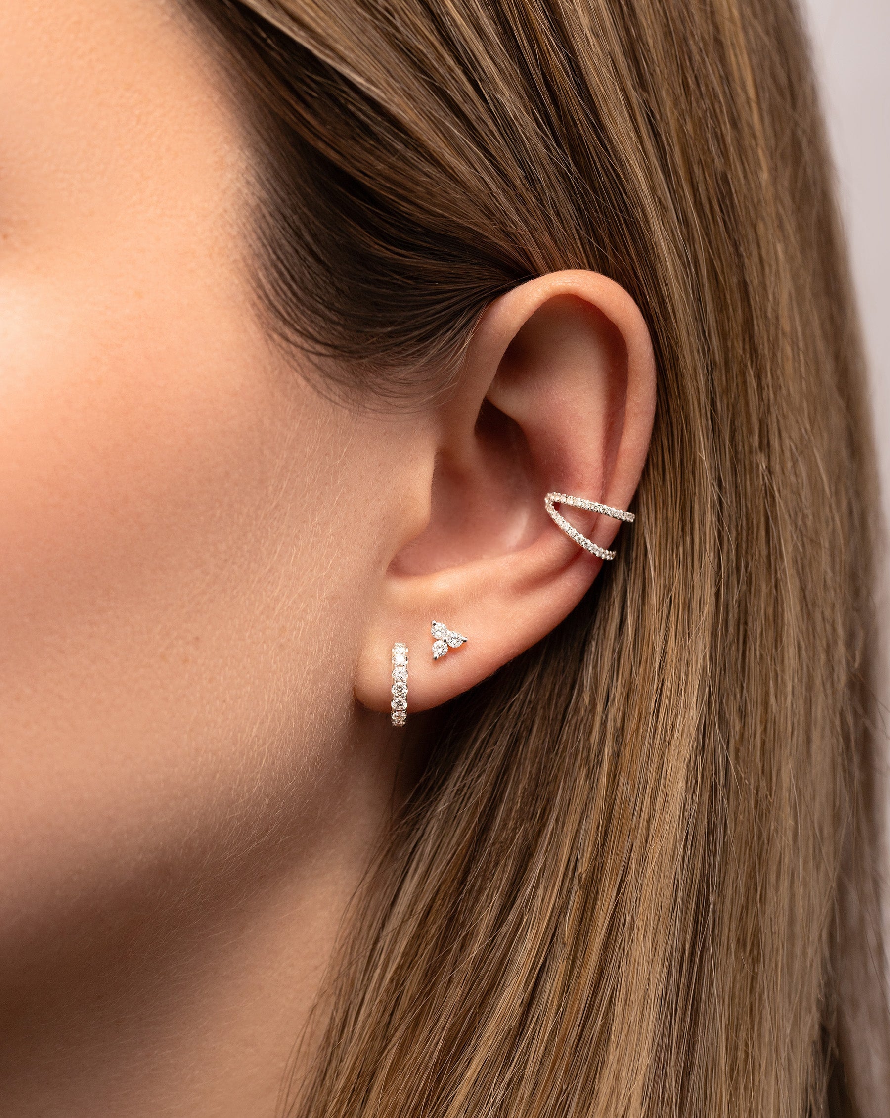 Diamond Trio Studs styled with petite jumbo diamond huggies and double row diamond ear cuff on model