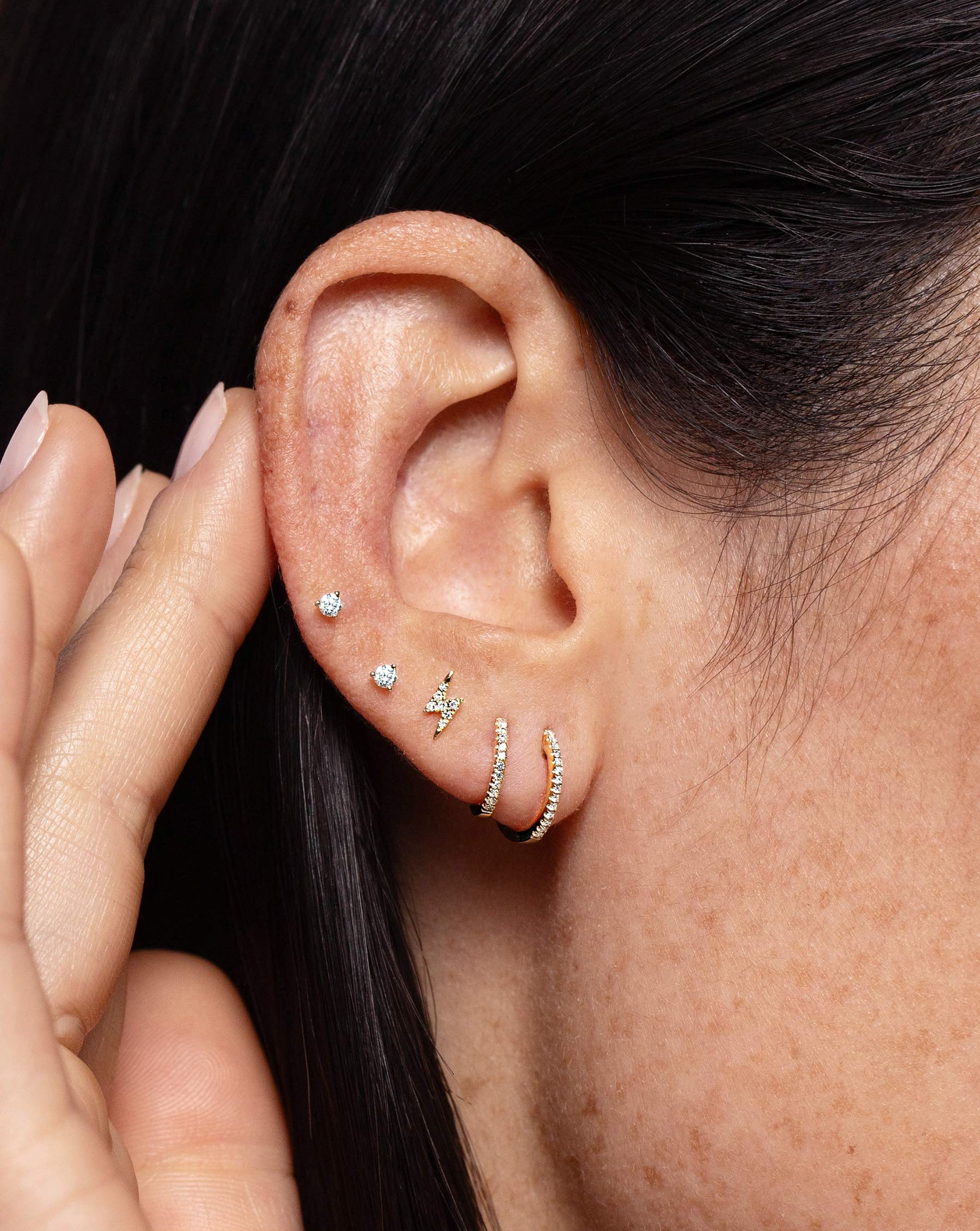 Two Tiny Diamond Studs worn in ear with the Mini Lightning Bold Studs, Petite Diamond Huggies and Diamond Huggies.
