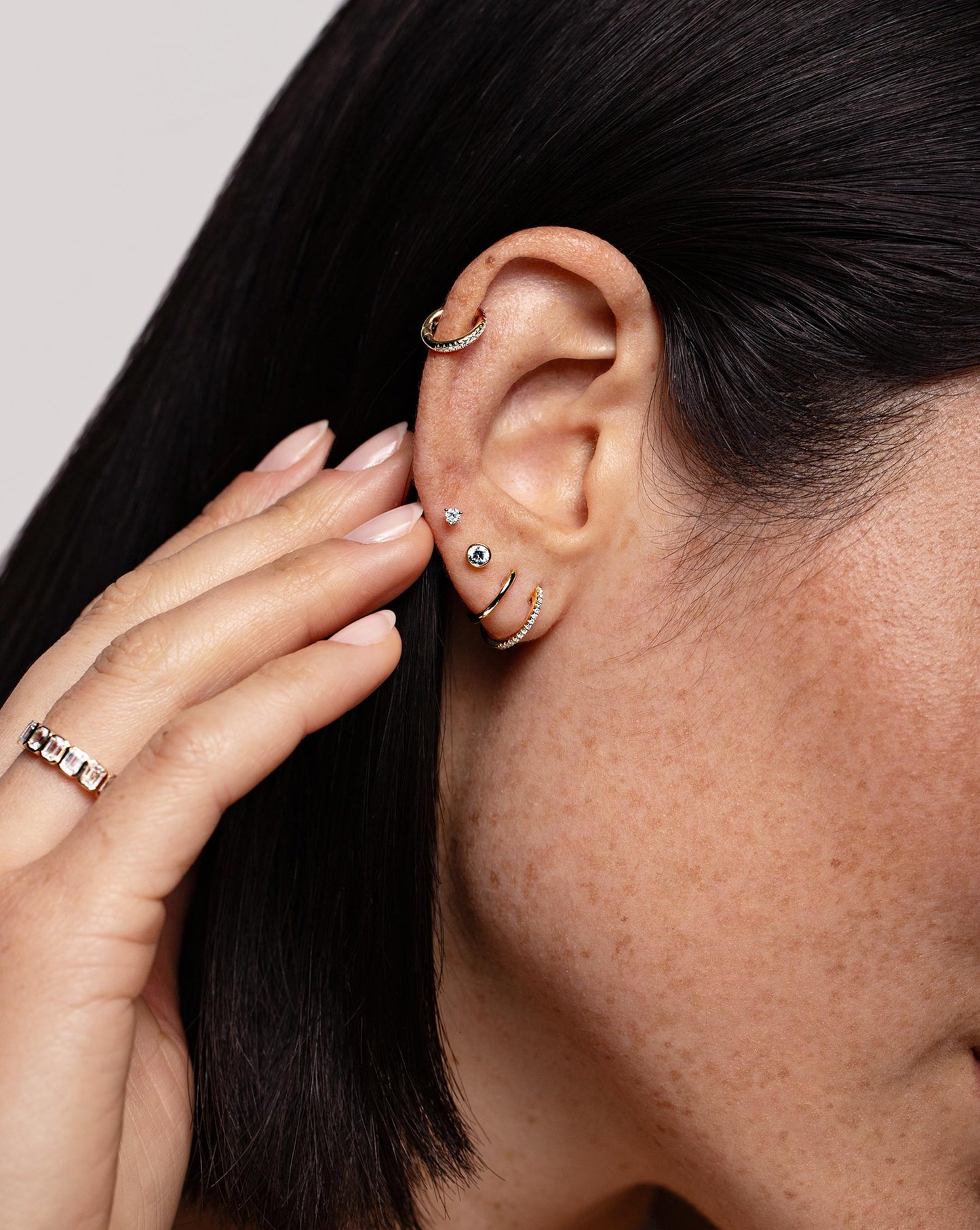 Tiny Diamond Studs worn in ear with the Petite Bezel-Set Diamond Stud, Classic Gold Huggies, Diamond Huggies and Mini Diamond Ear Cuff in ear.