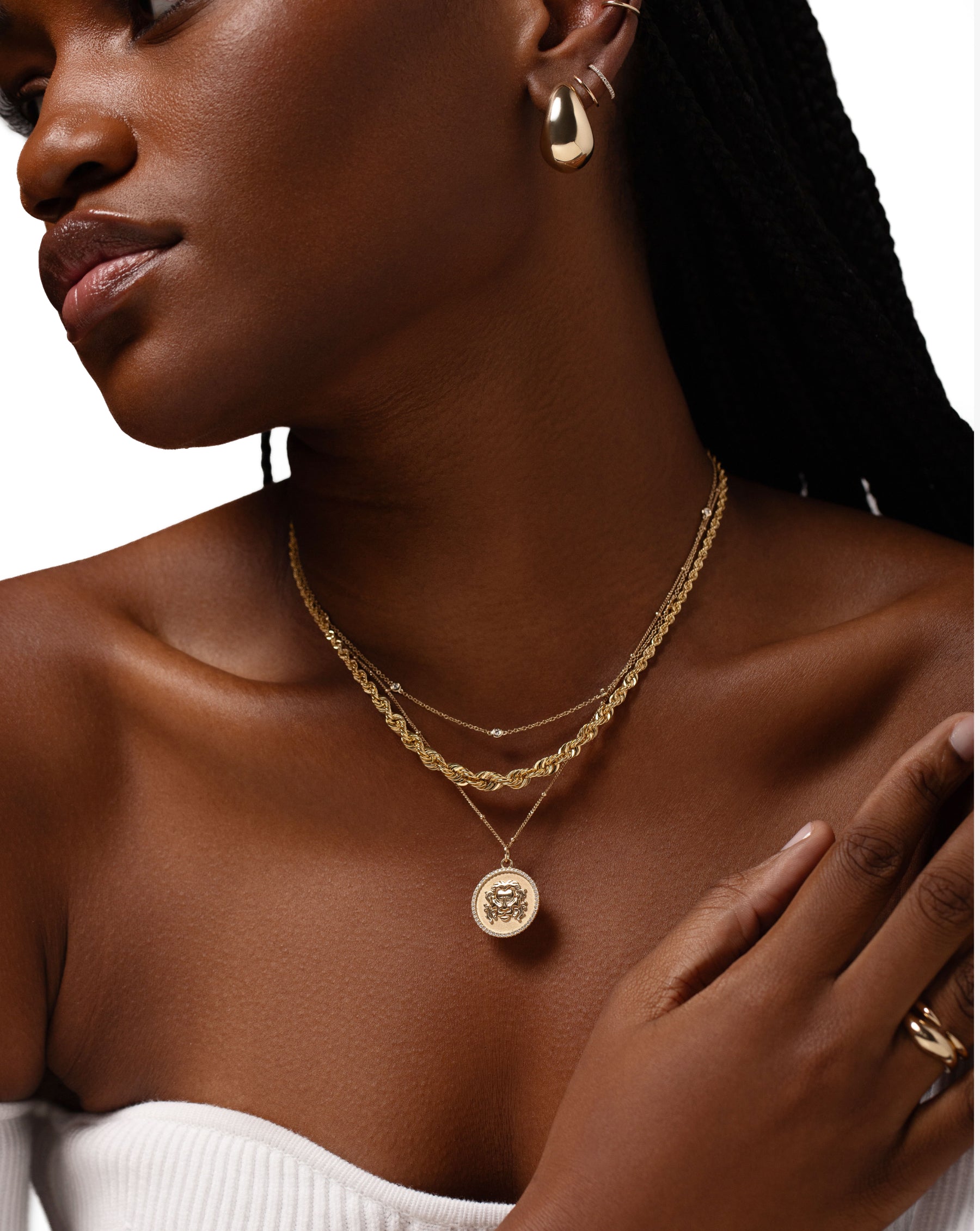 bezel set round diamond station necklace, gold rope chain necklace, and zodiac medallion necklace on model global