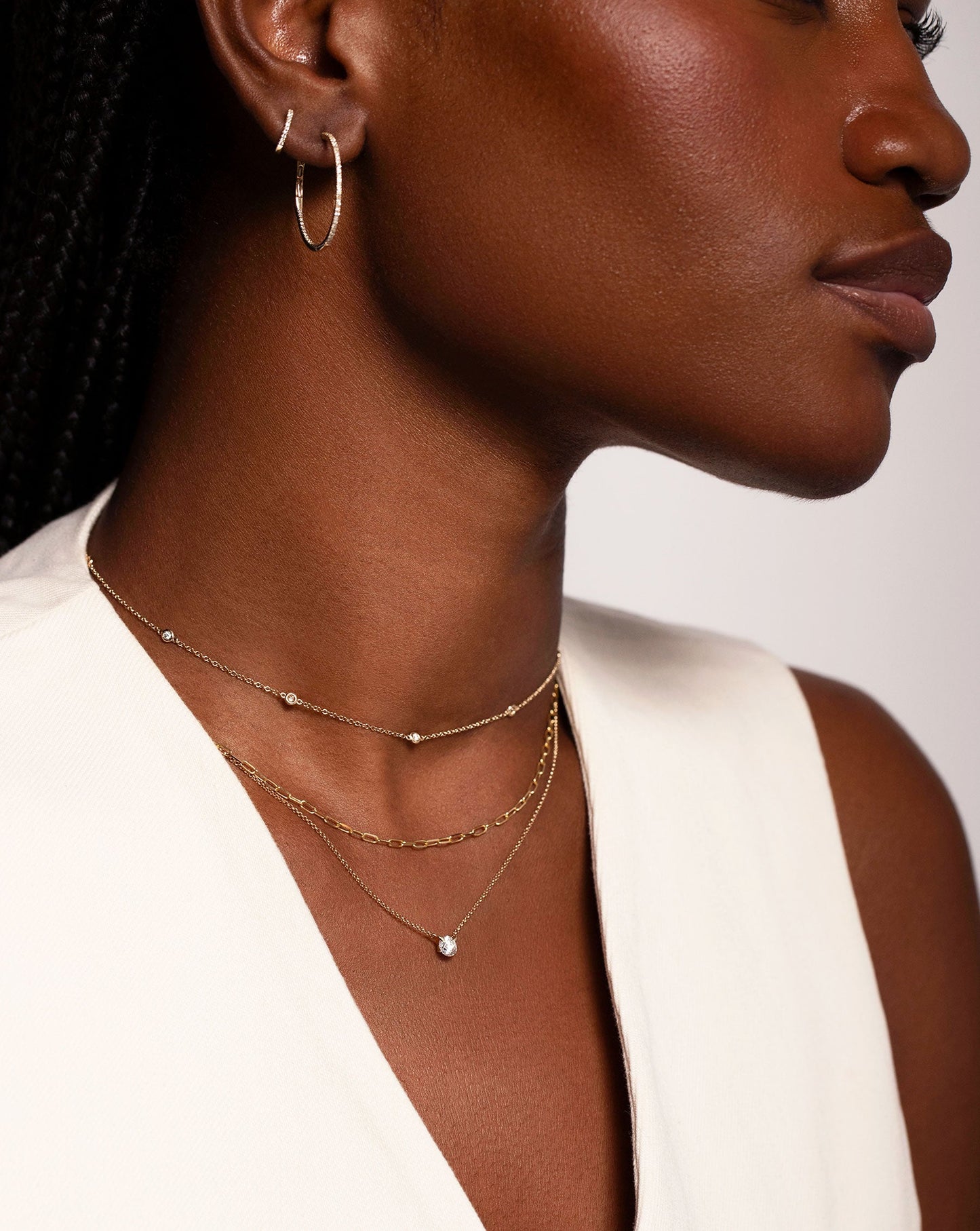 Half Carat Floating Diamond Necklace worn around neck with the Multiway Diamond Bezel Necklace + Double Wrap Bracelet and the Multiway Mini Link Necklace + Double Wrap Bracelet. Model is also wearing the Diamond Hoops and Petite Diamond Huggie in her ear. 
