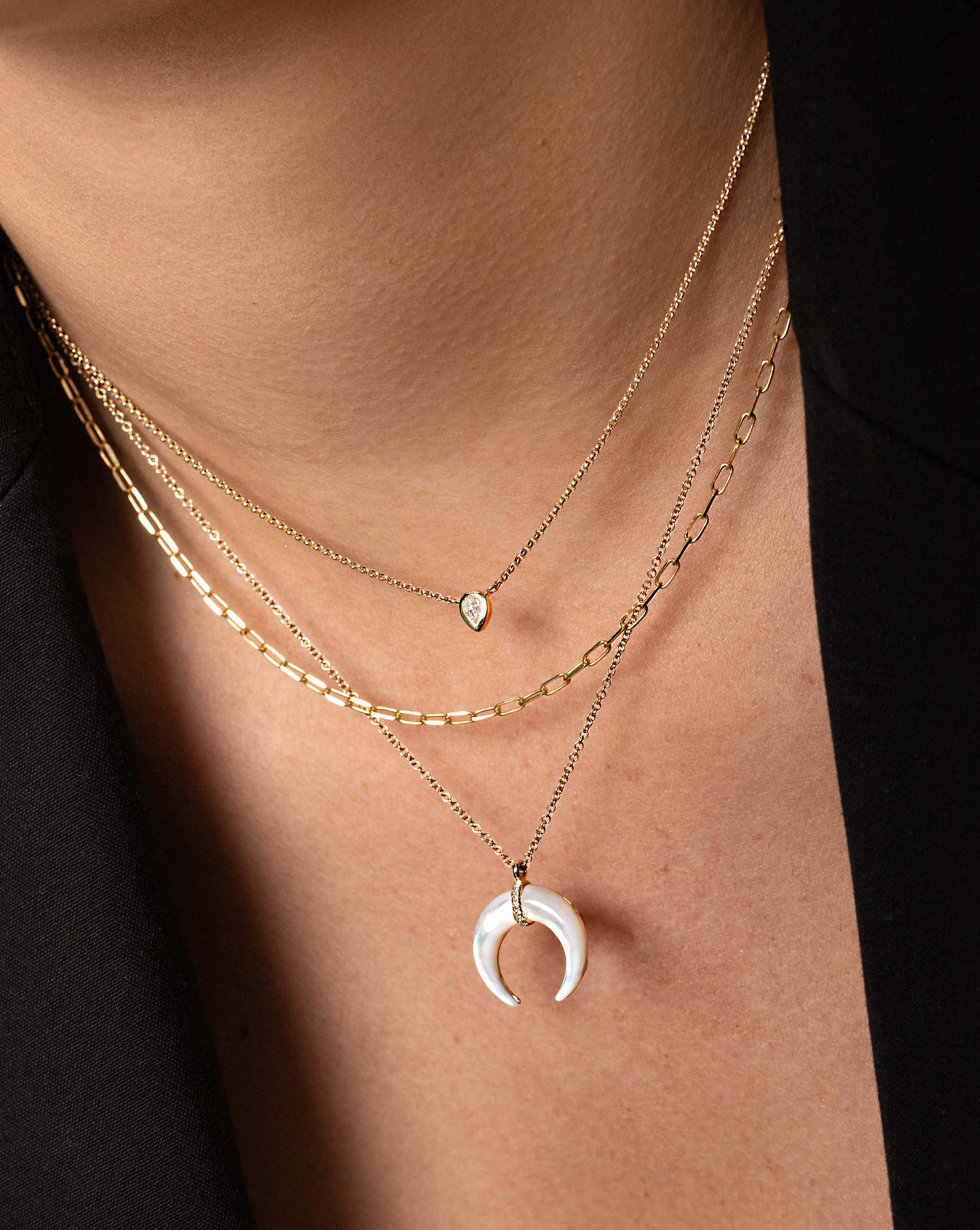 Mother of Pearl + Pavé Horn Necklace styled with mini link chain necklace and pear mixed shape diamond necklace on model