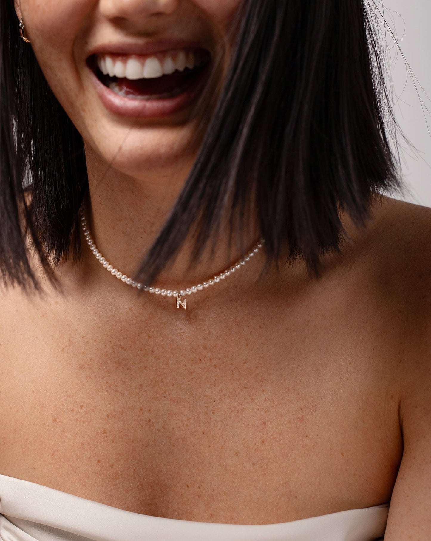 Laughing model wearing the Pearl + Pavé Initial Choker in the letter N