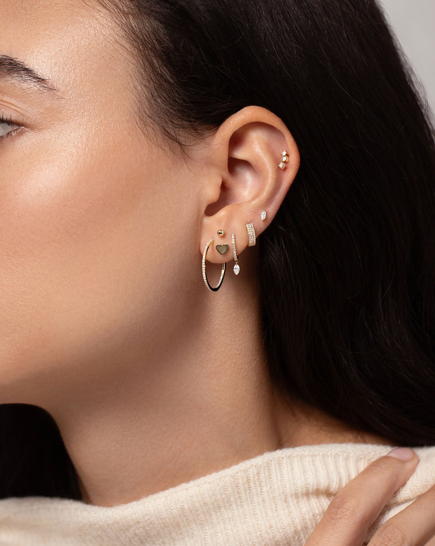 Curved Trio Studs styled as a top ear piercing with other gold and diamond earrings on model
