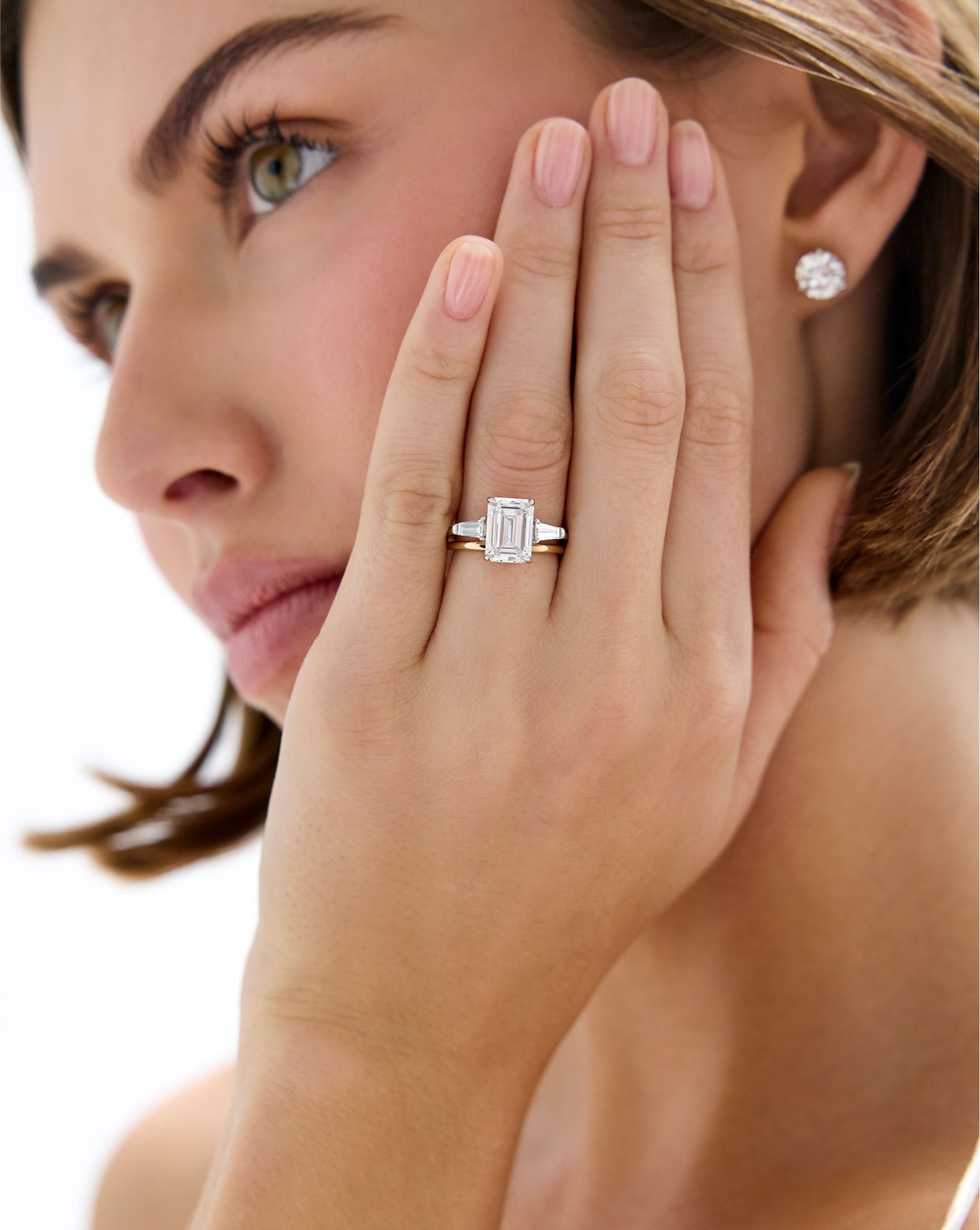 Model wearing Whisper Thin Band stacked with Emerald Three Stone Engagement Ring global