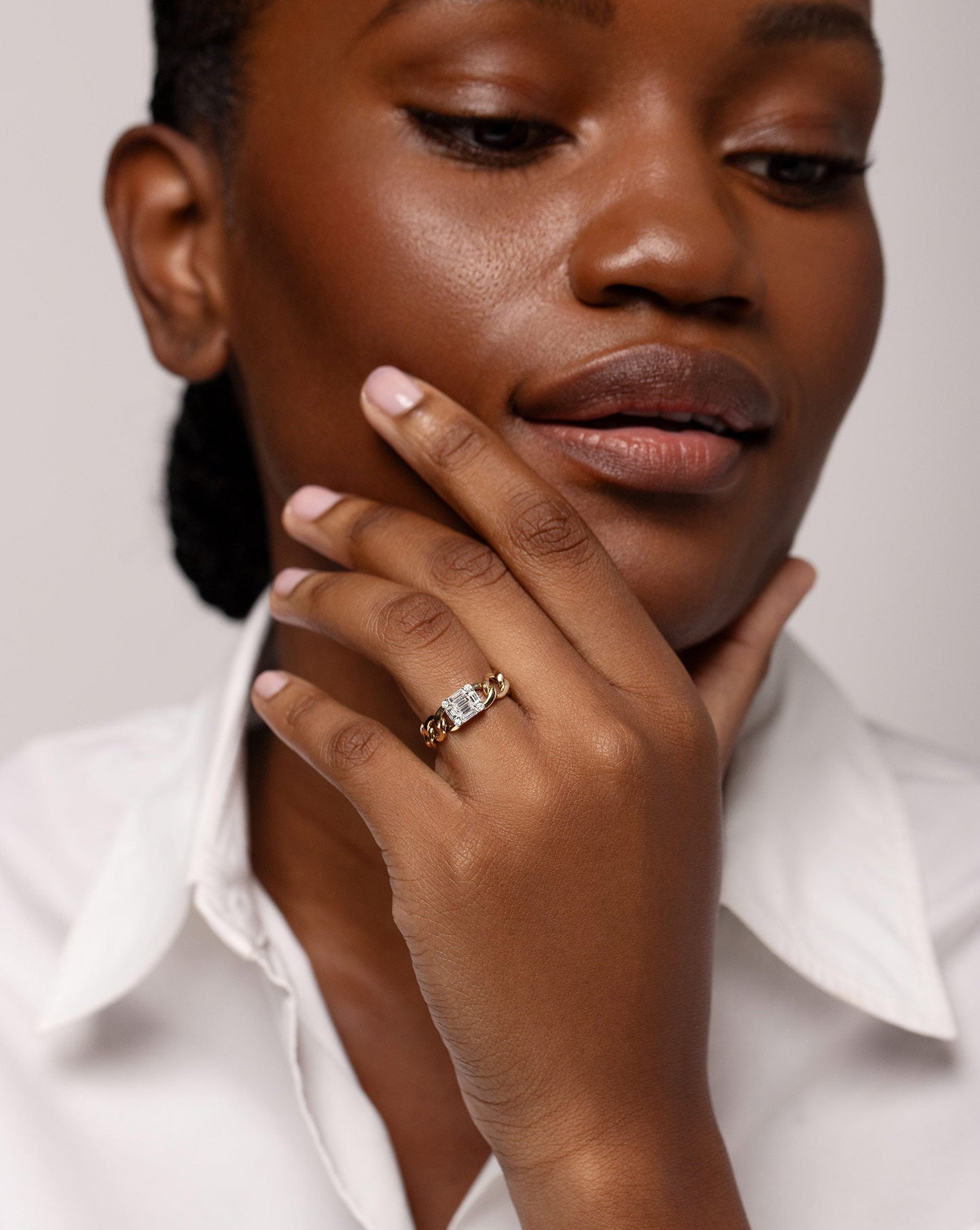 Emerald Illusion Curb Chain Ring shown on ring finger of hand touching face of model