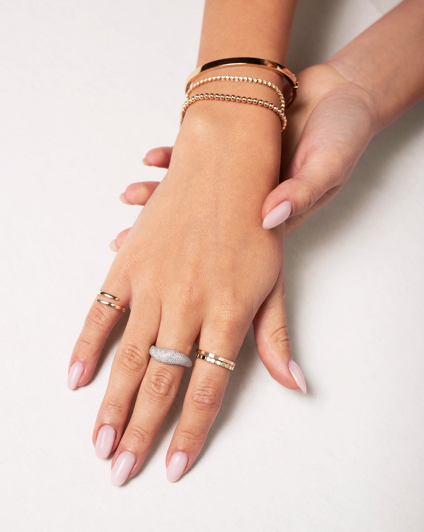 Faceted Stackable Ring worn on hand with the Geometric Stackable Ring, Pave Movement Cloud Ring and Open Gold Wrap Ring. Model is also wearing the Petite Gold Bead Bracelet, Mini Diamond Tennis Bracelet and Stackable Gold Bangle.