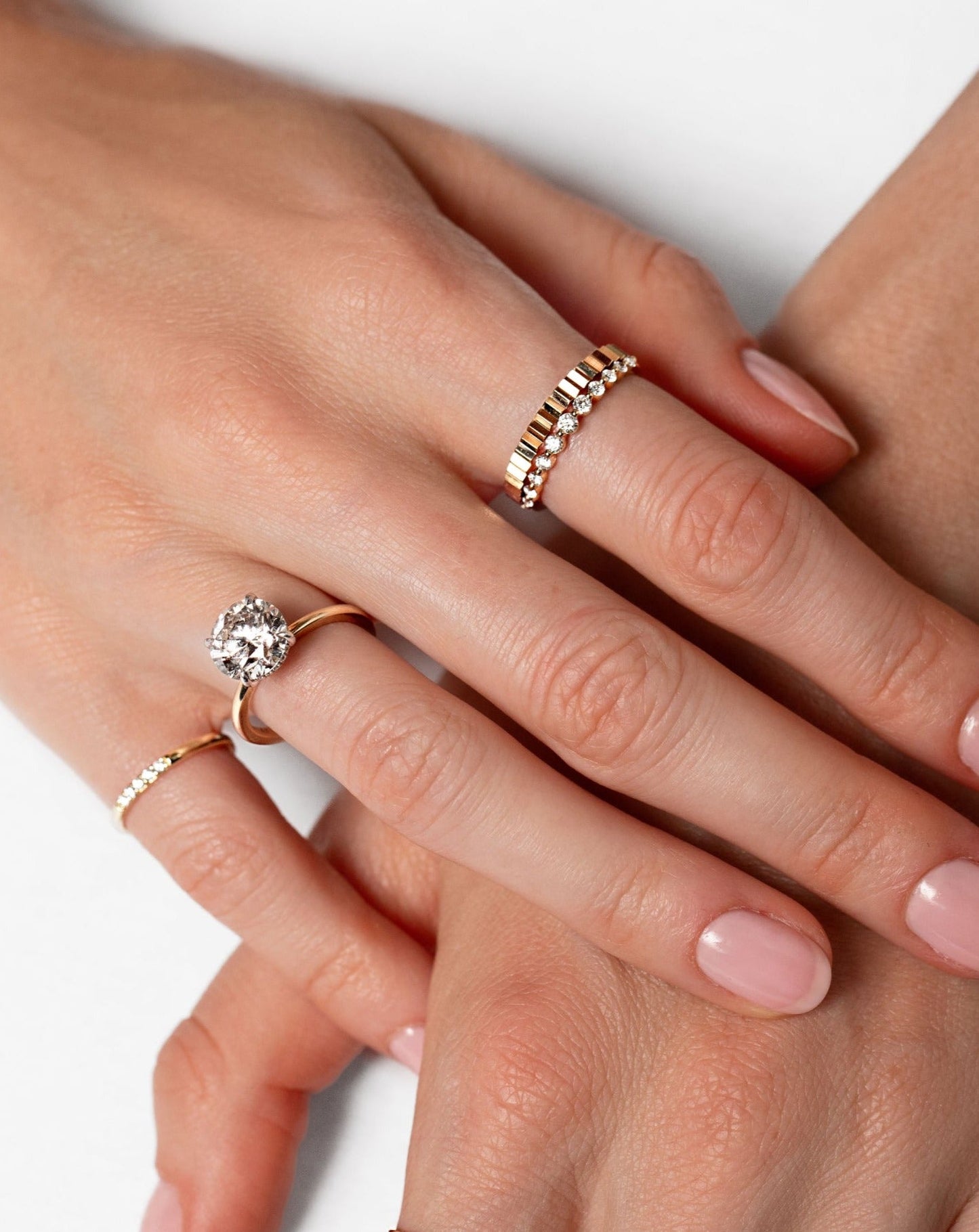 14k gold and diamond pink ring, round cut diamond engagement ring, gold fluted ring, graduated diamond ring, gold cut out roman numeral ring, and two stone diamond open ring on model