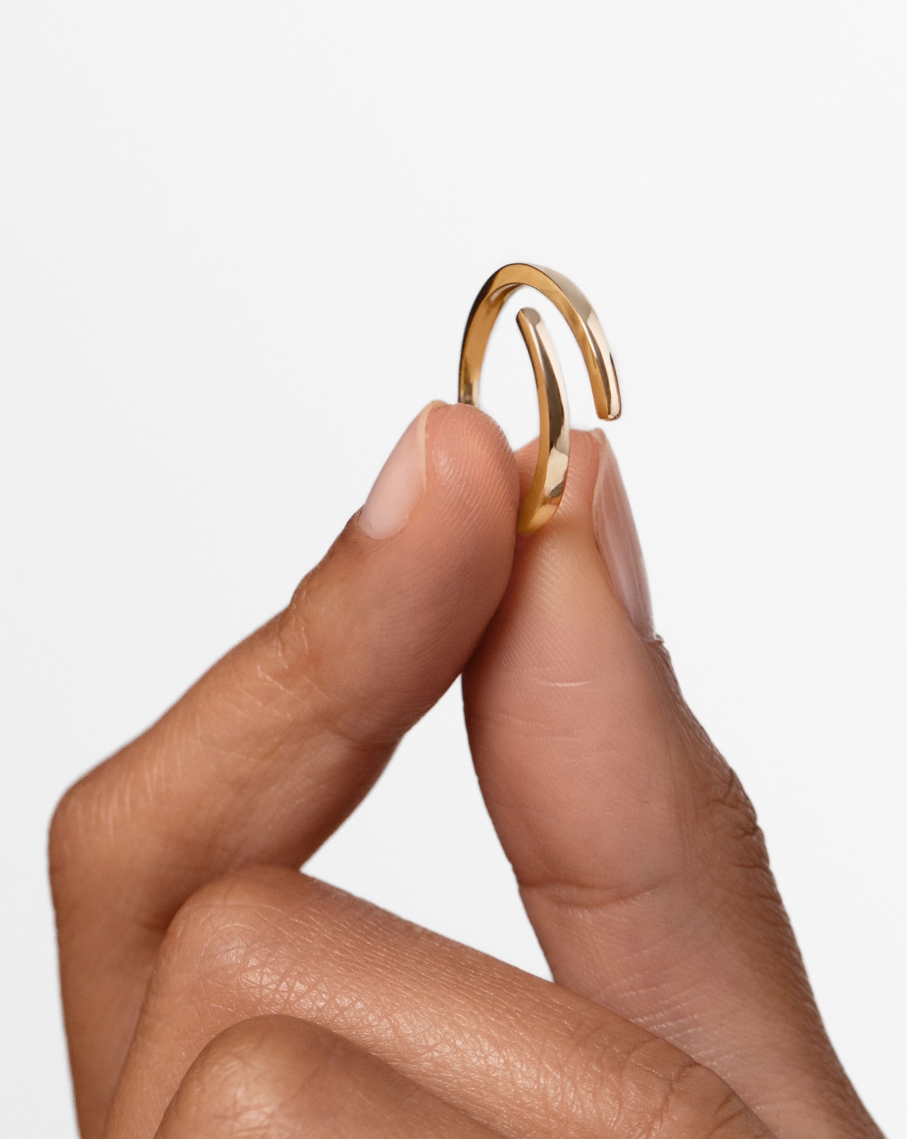 model holding open gold wrap ring in between fingers