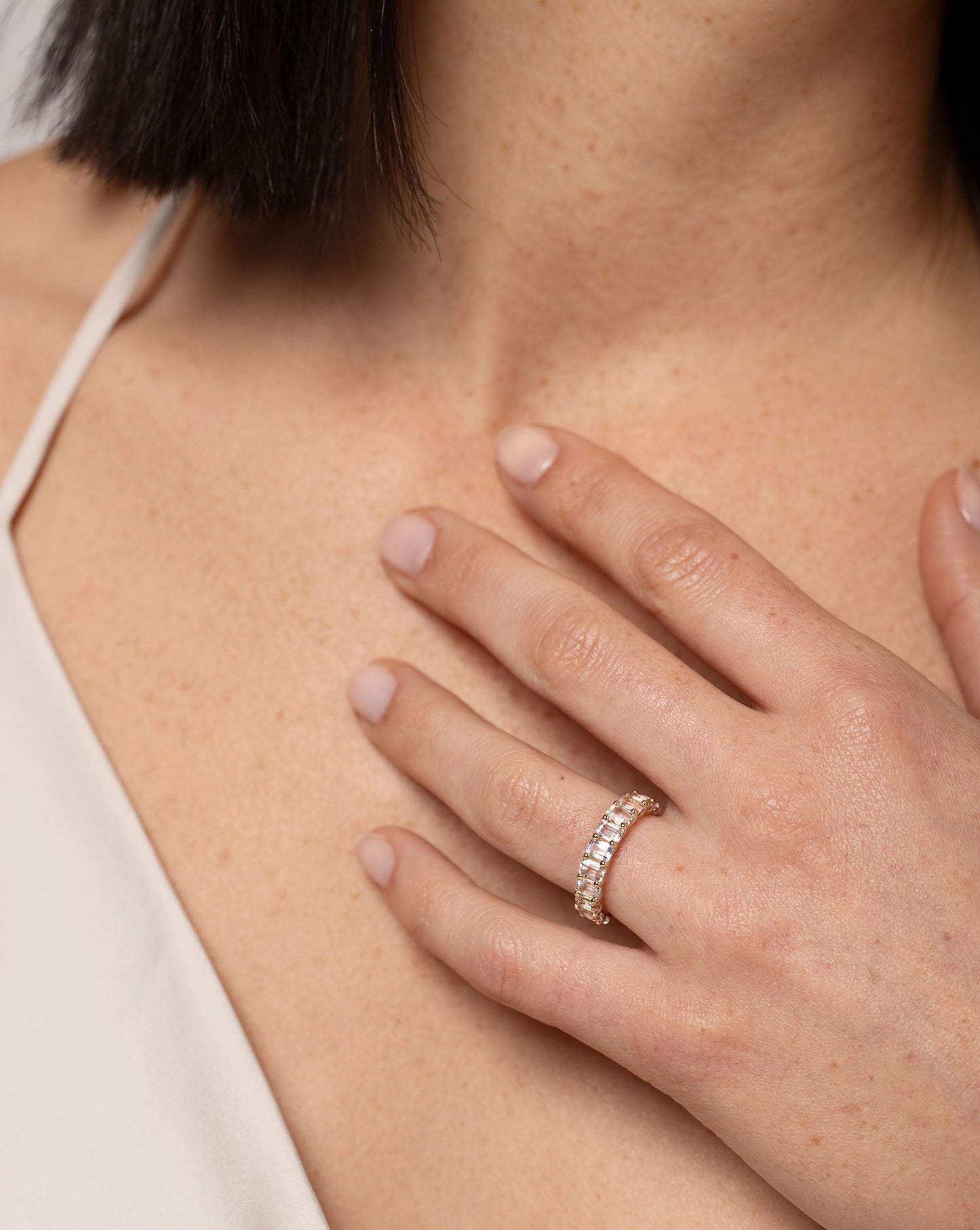 Petite Emerald Cut White Topaz Ring on model with hand on chest