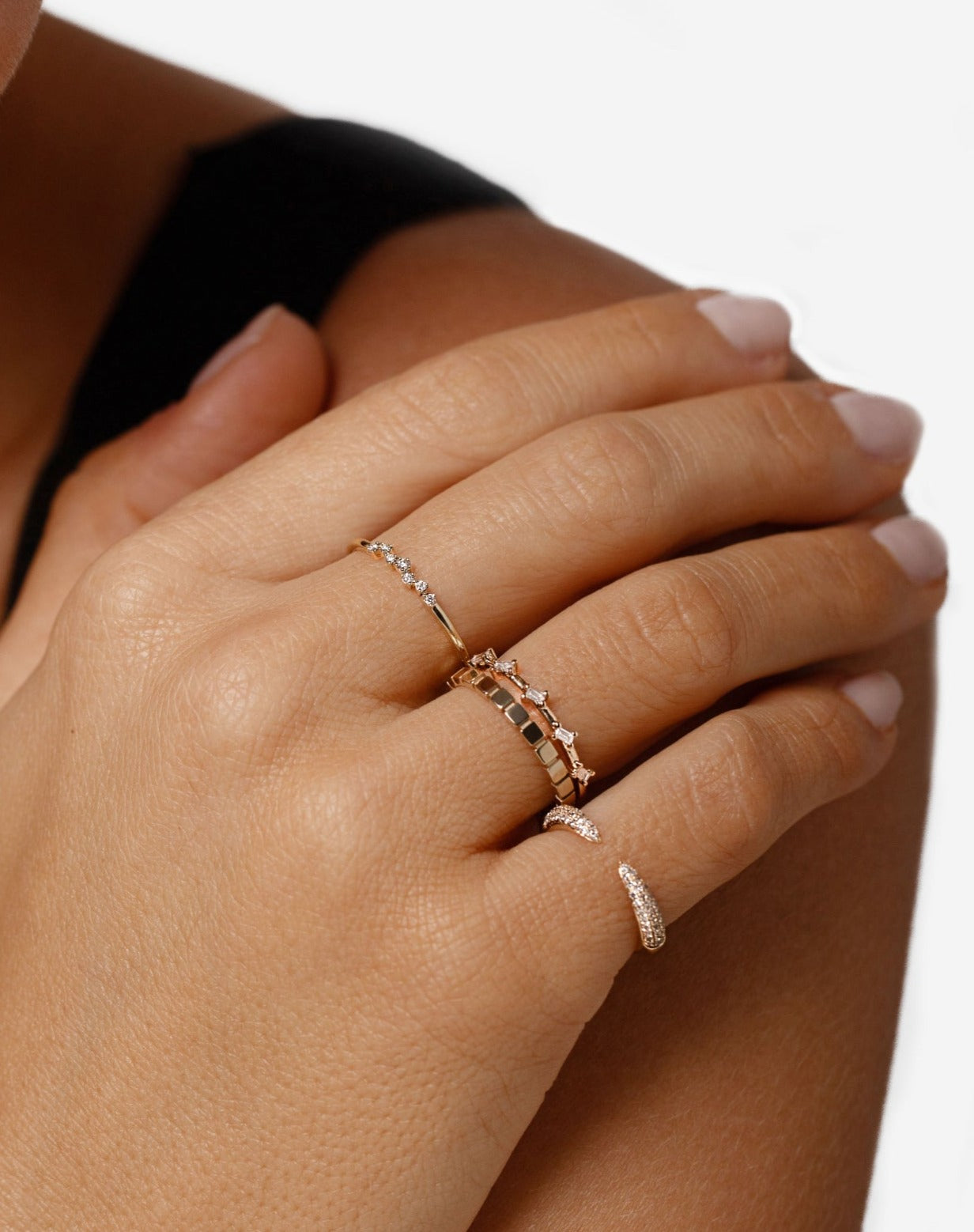 Model touching hand on shoulder wearing Triple Row Diamond Claw Ring, Scattered Diamond Stackable Ring, Geometric Stackable Ring and Baguette Distance Ring