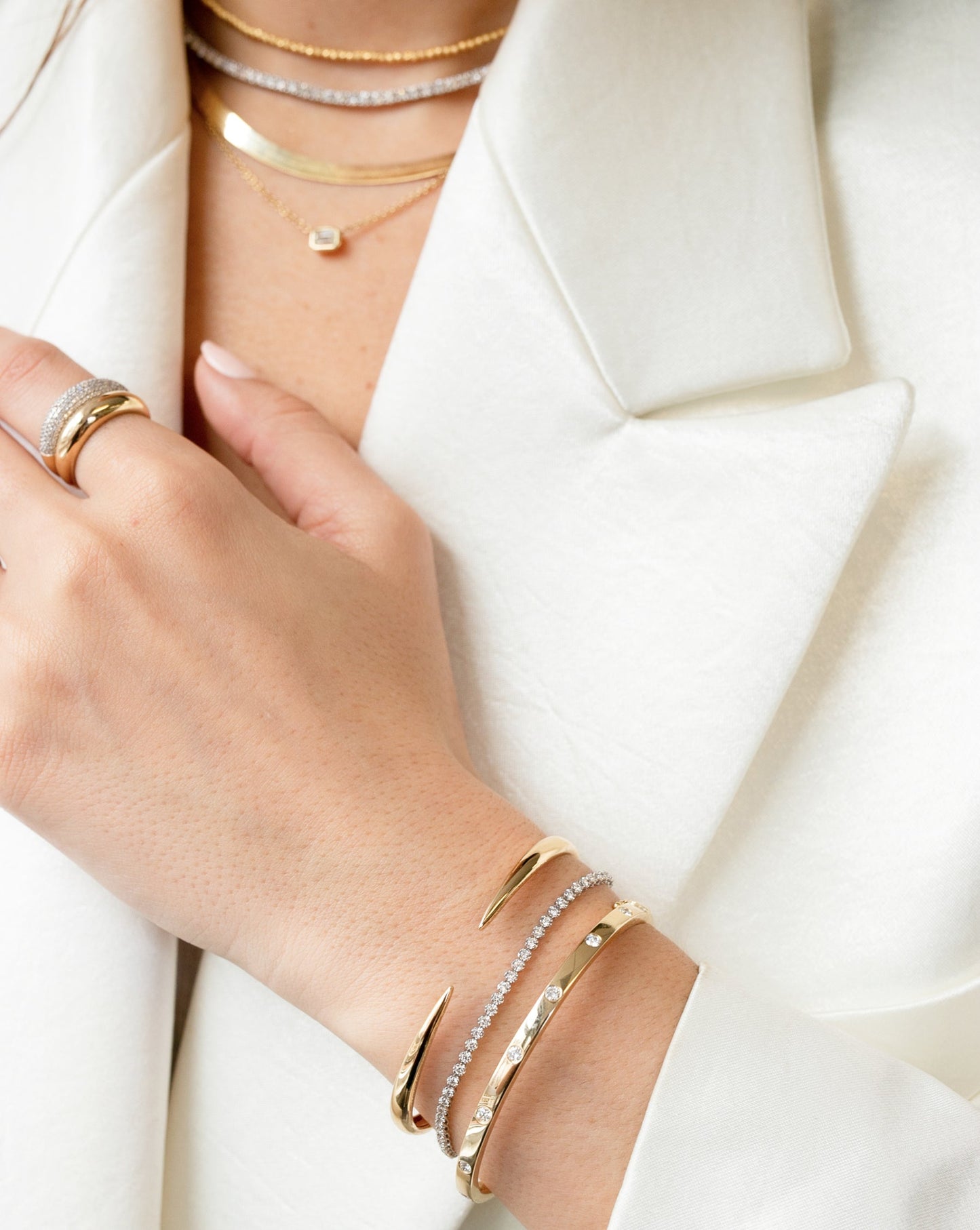 four gold and diamond necklaces, gold and diamond cloud ring, gold cloud ring, gold claw cuff, mini diamond tennis bracelet, and gold and diamond bangle on model