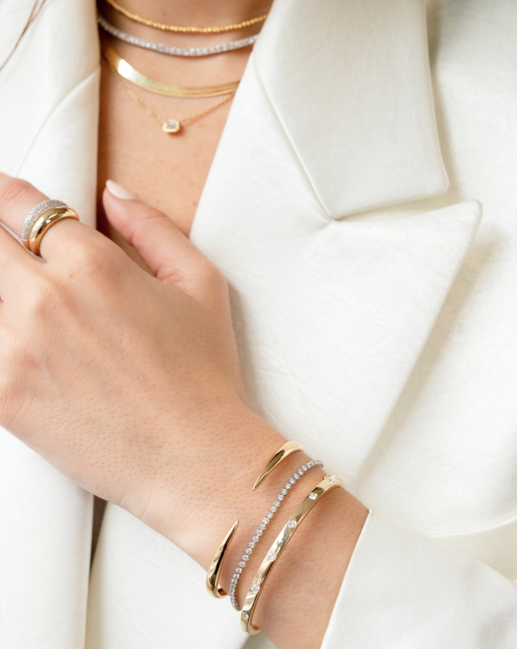 four gold and diamond necklaces, gold and diamond cloud ring, gold cloud ring, gold claw cuff, mini diamond tennis bracelet, and gold and diamond bangle on model