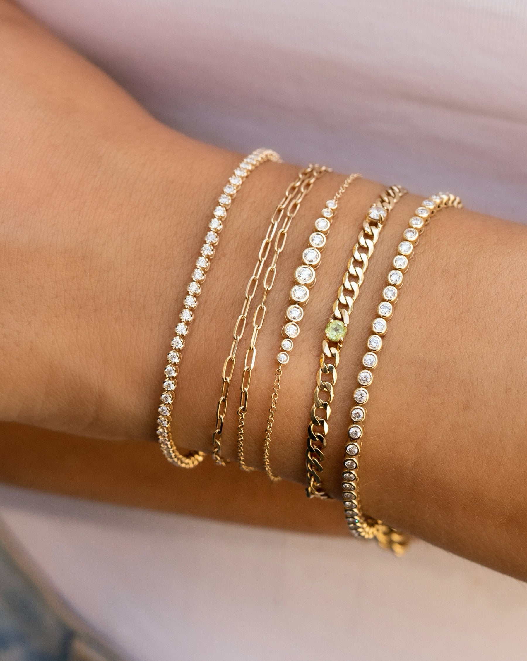 Mini diamond tennis bracelet, double wrap gold link bracelet, graduated bezel set diamond bracelet, gold chain bracelet with one peridot stone and one diamond, bezel-set round diamond tennis bracelet on model