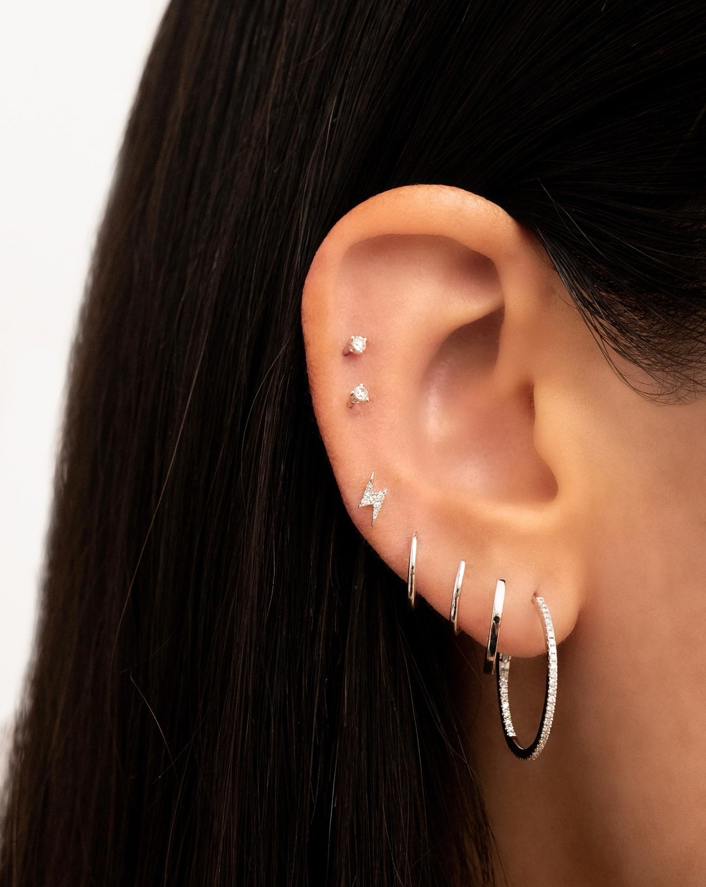 14k White Gold Mini Lighting Bolt Studs shown on Ear with a multitude of hoops and studs